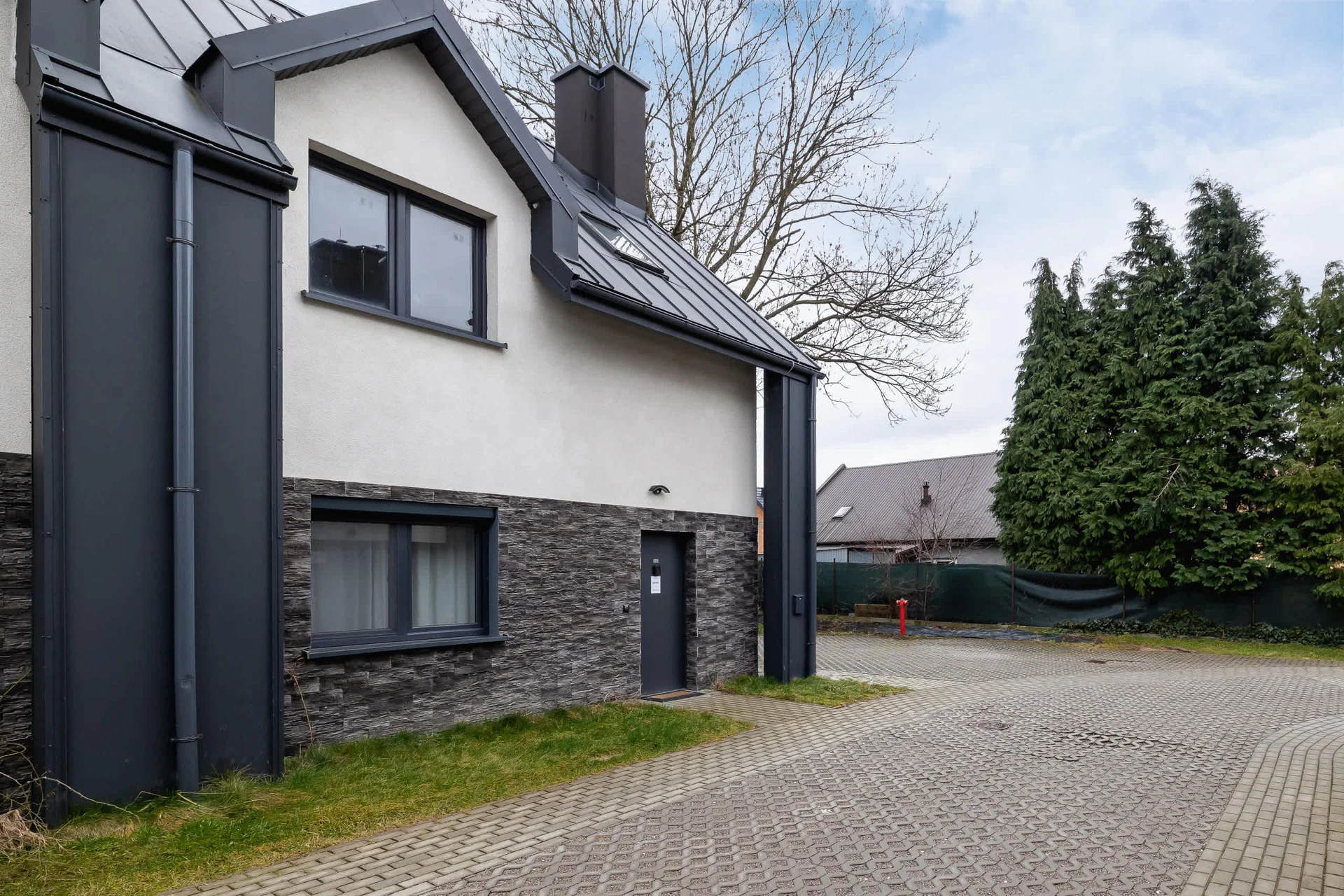An exterior view of a modern house, showcasing clean architectural lines and a combination of light and dark facade materials.
