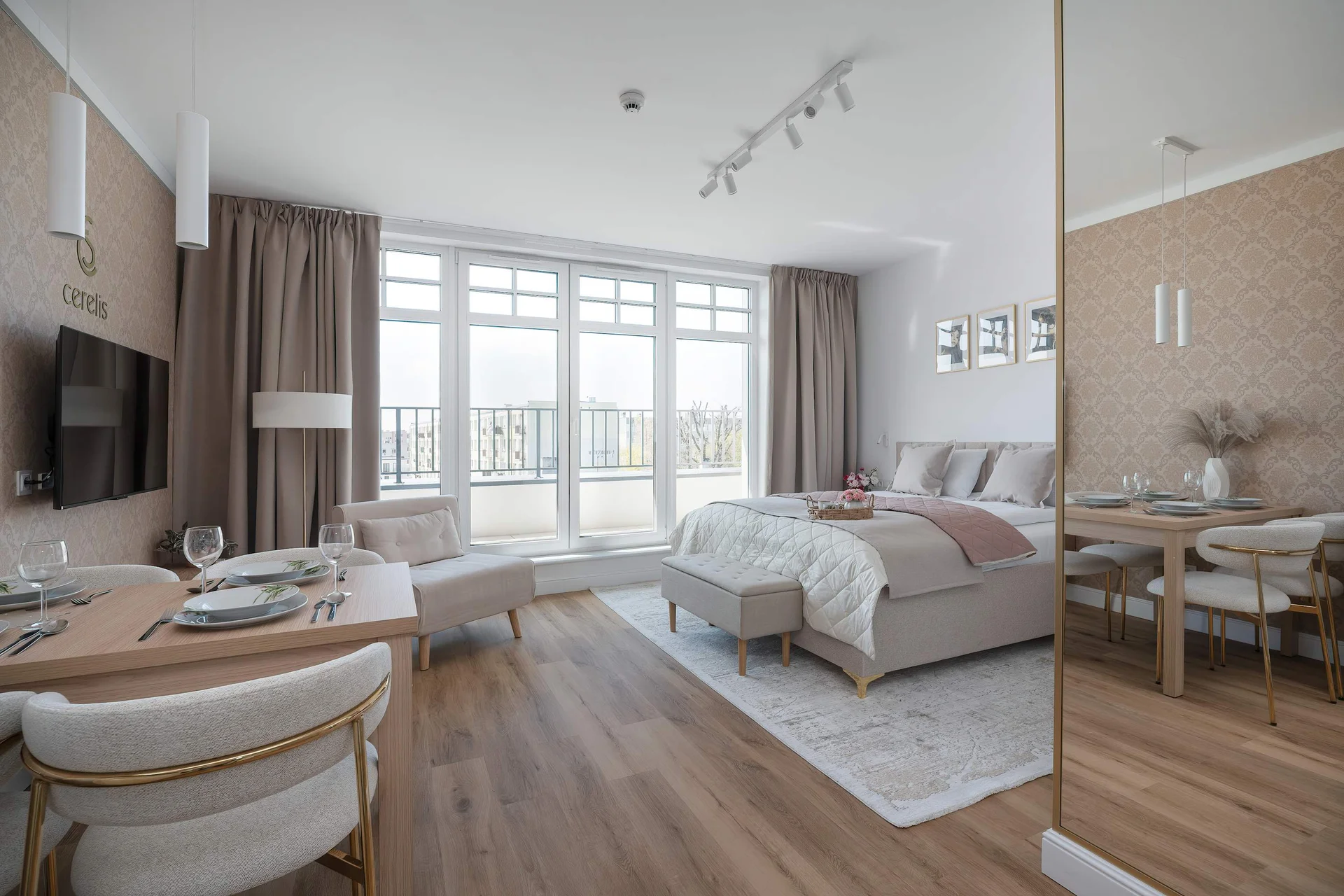 A modern open-space apartment with a bed, dining area, and large windows bringing in plenty of natural light.