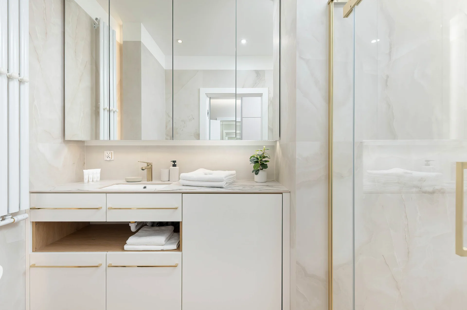 Bright bathroom with modern vanity, marble finishes and illuminated mirror