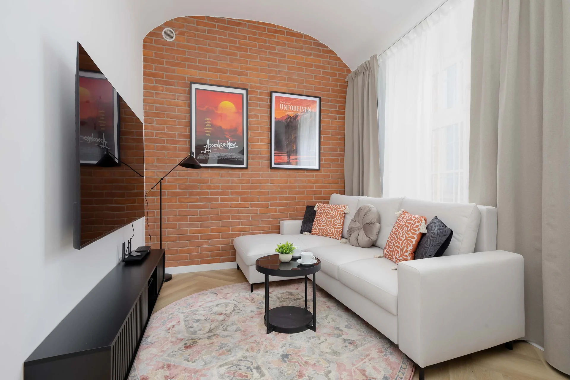 Bright living area with a comfortable sofa, TV, and stylish brick accent wall.