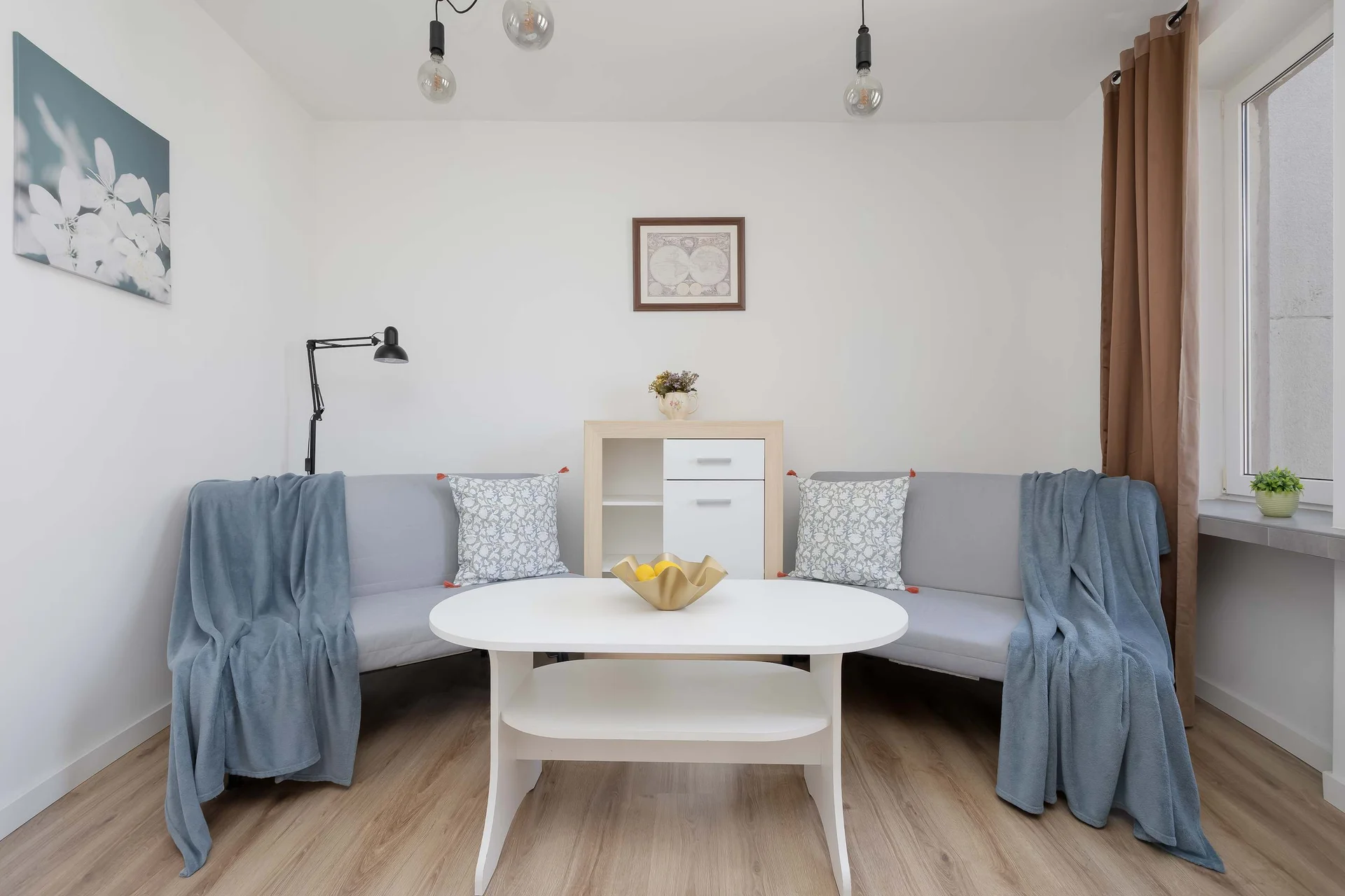 Bright second bedroom featuring two comfortable sofa beds, a dining table, and large windows providing plenty of natural light.