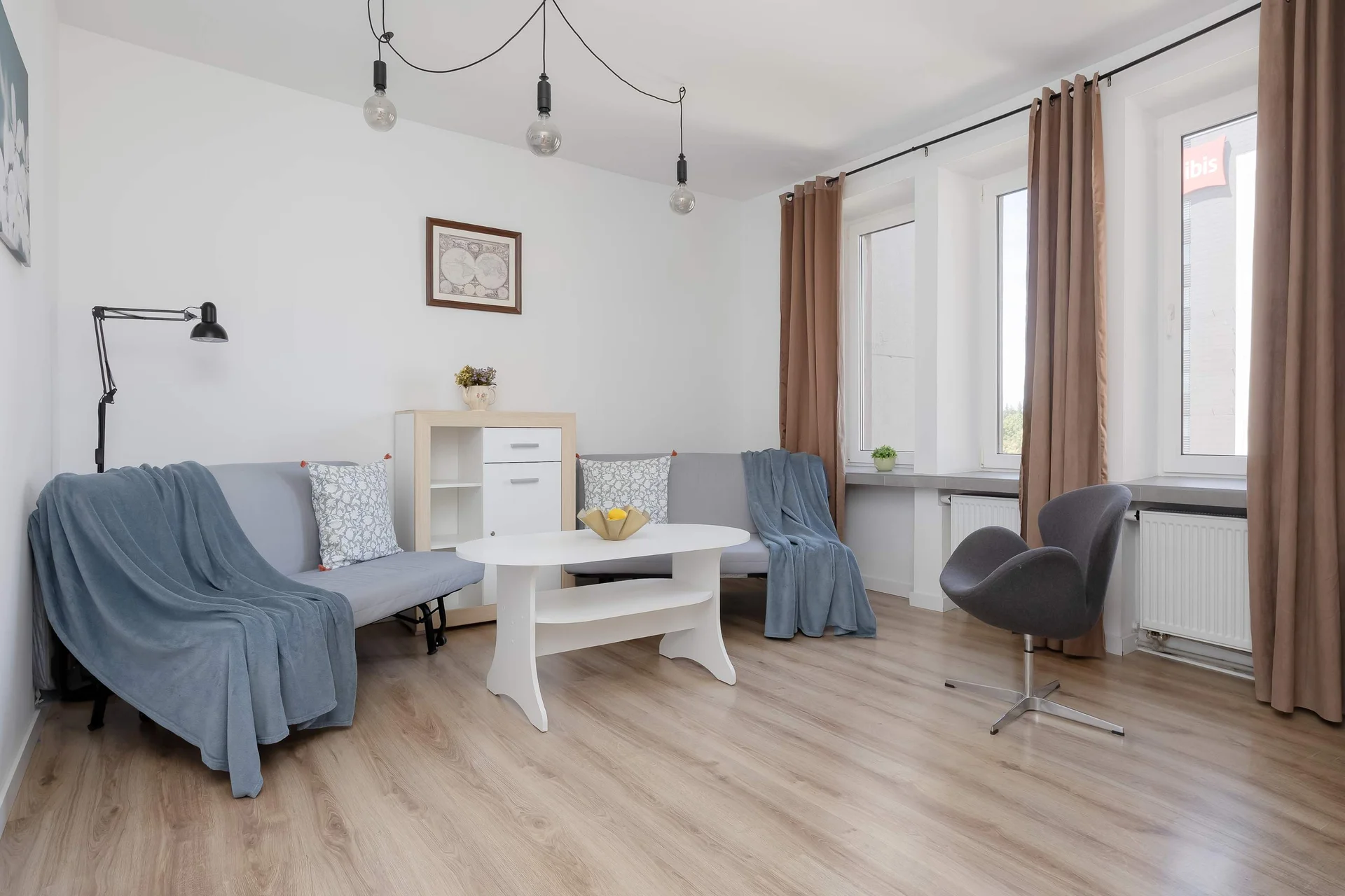 Bright second bedroom featuring two comfortable sofa beds, a dining table, and large windows providing plenty of natural light.