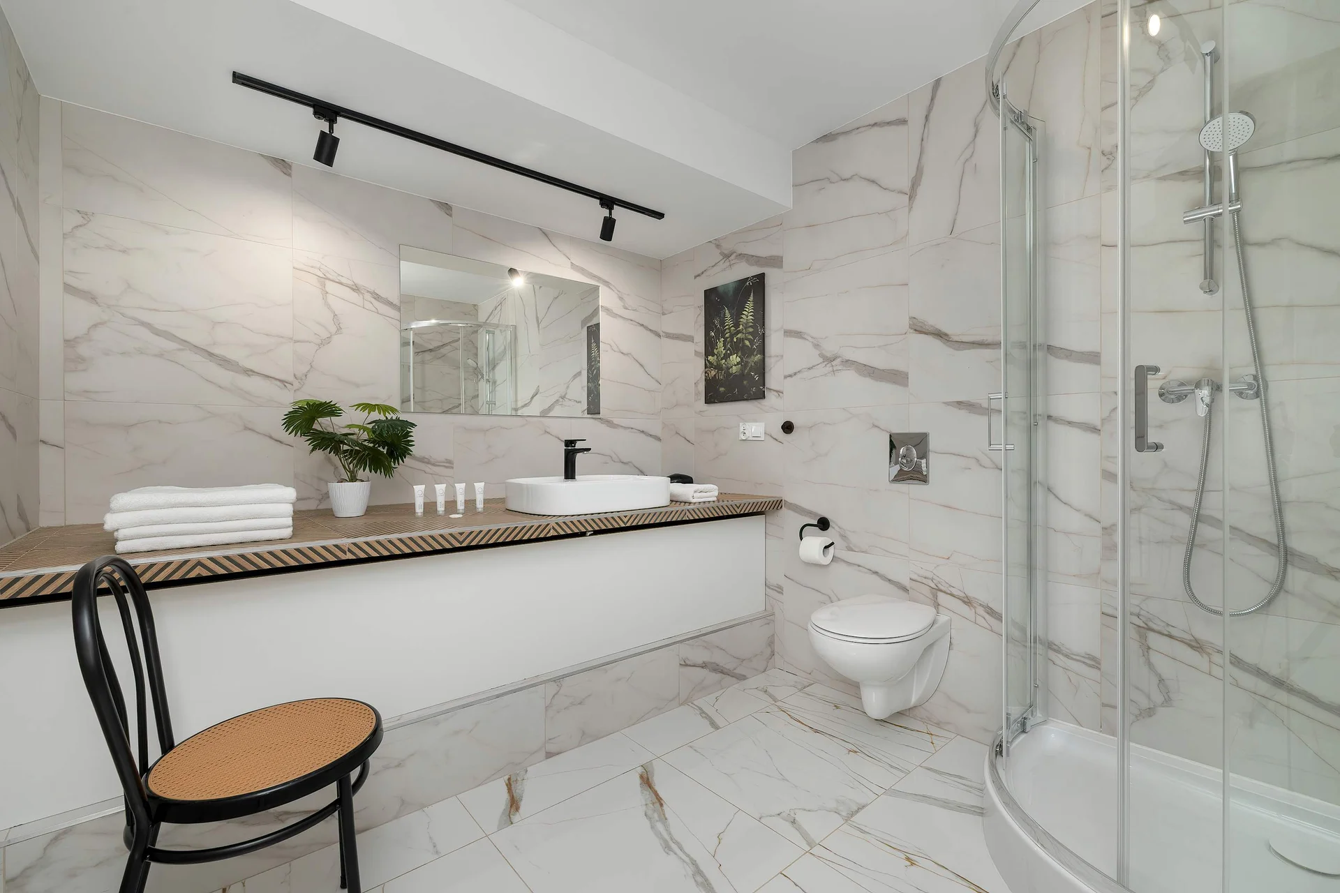 Contemporary bathroom with a walk-in rainfall shower, vanity sink and marble-style finishes.