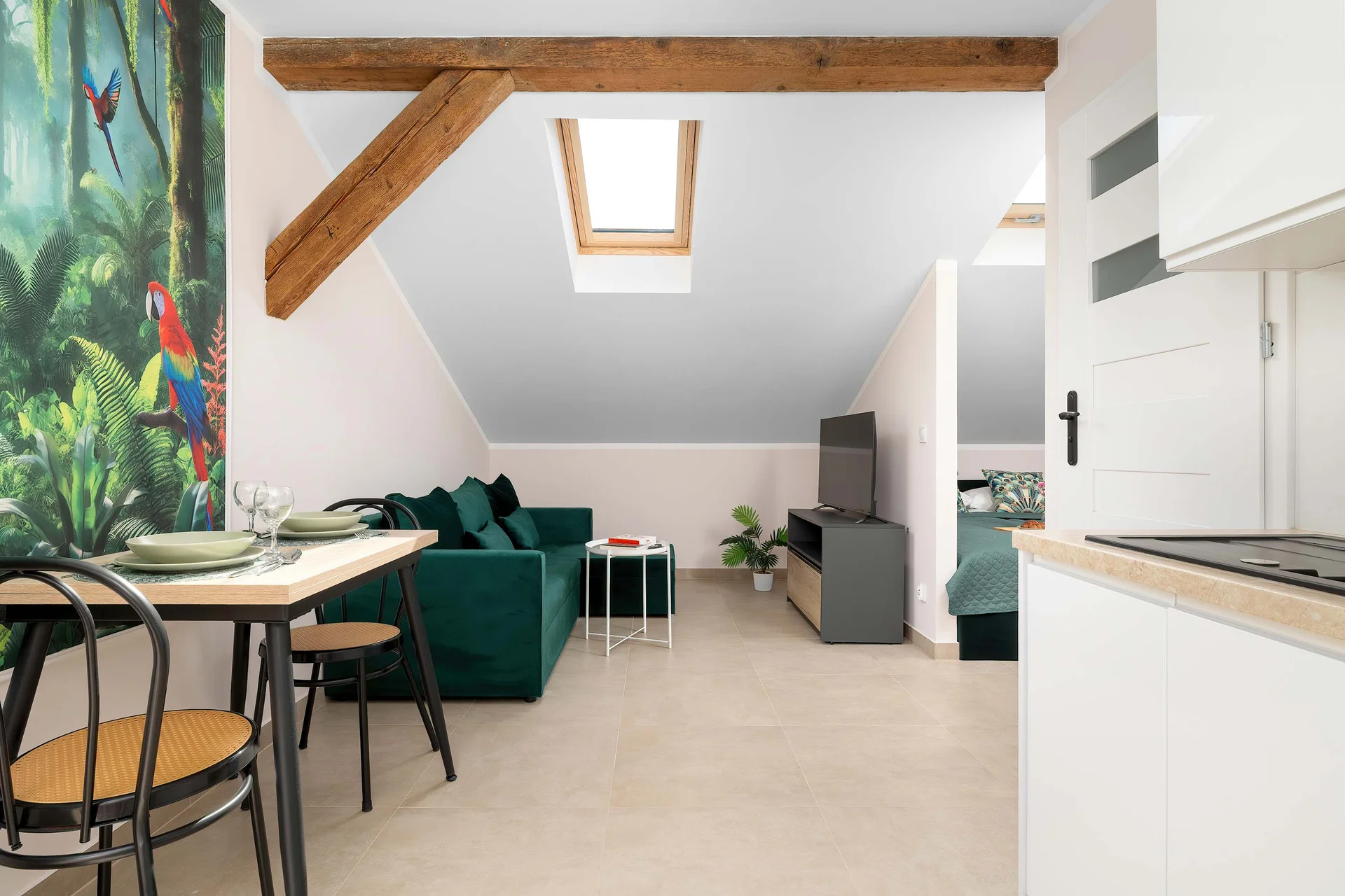 Open-plan studio combining the dining area, kitchenette and lounge with elegant tropical wall art.