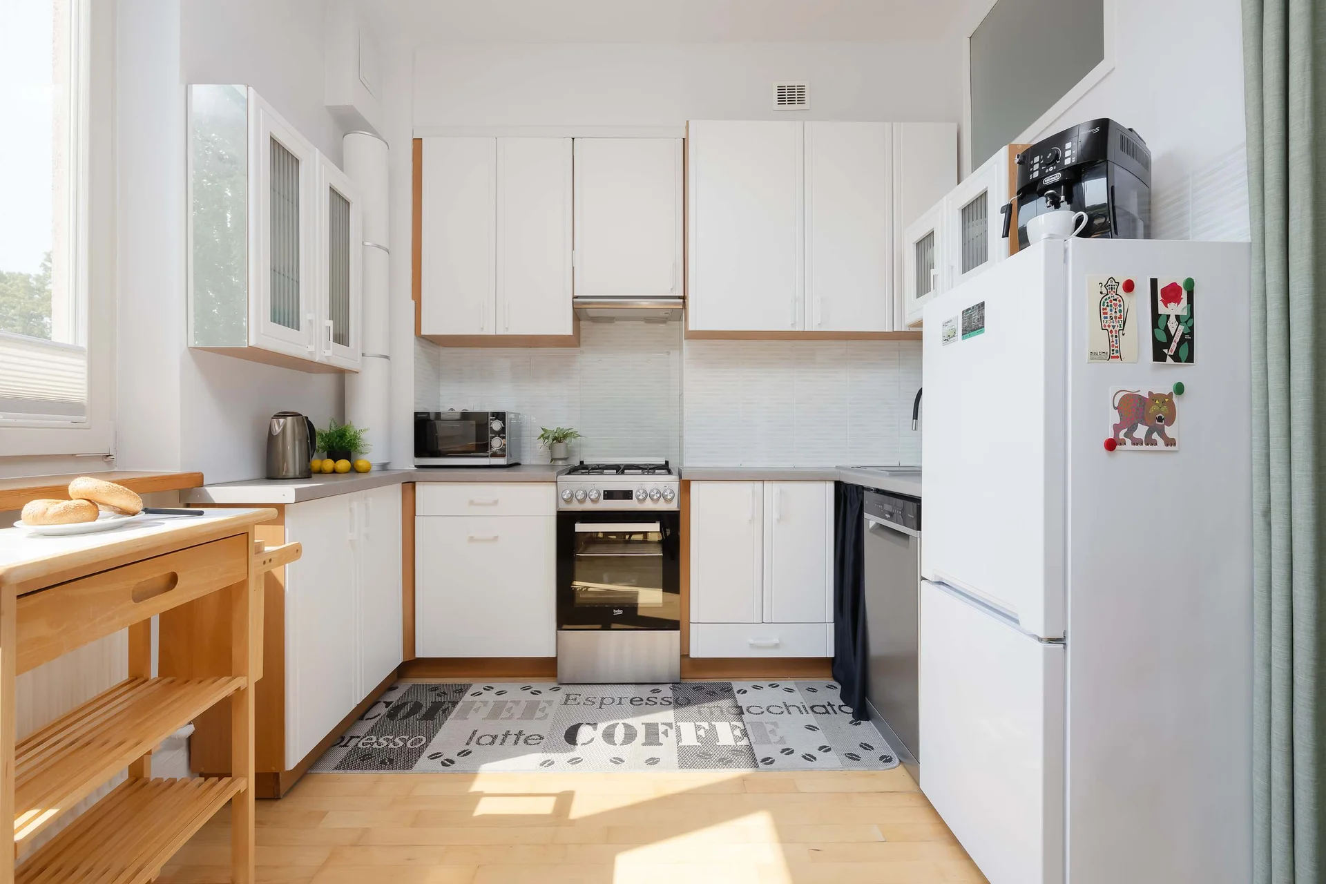 A functional kitchen features white cabinetry, wooden countertops, and modern appliances arranged along two walls. The compact layout provides everything needed for everyday cooking.