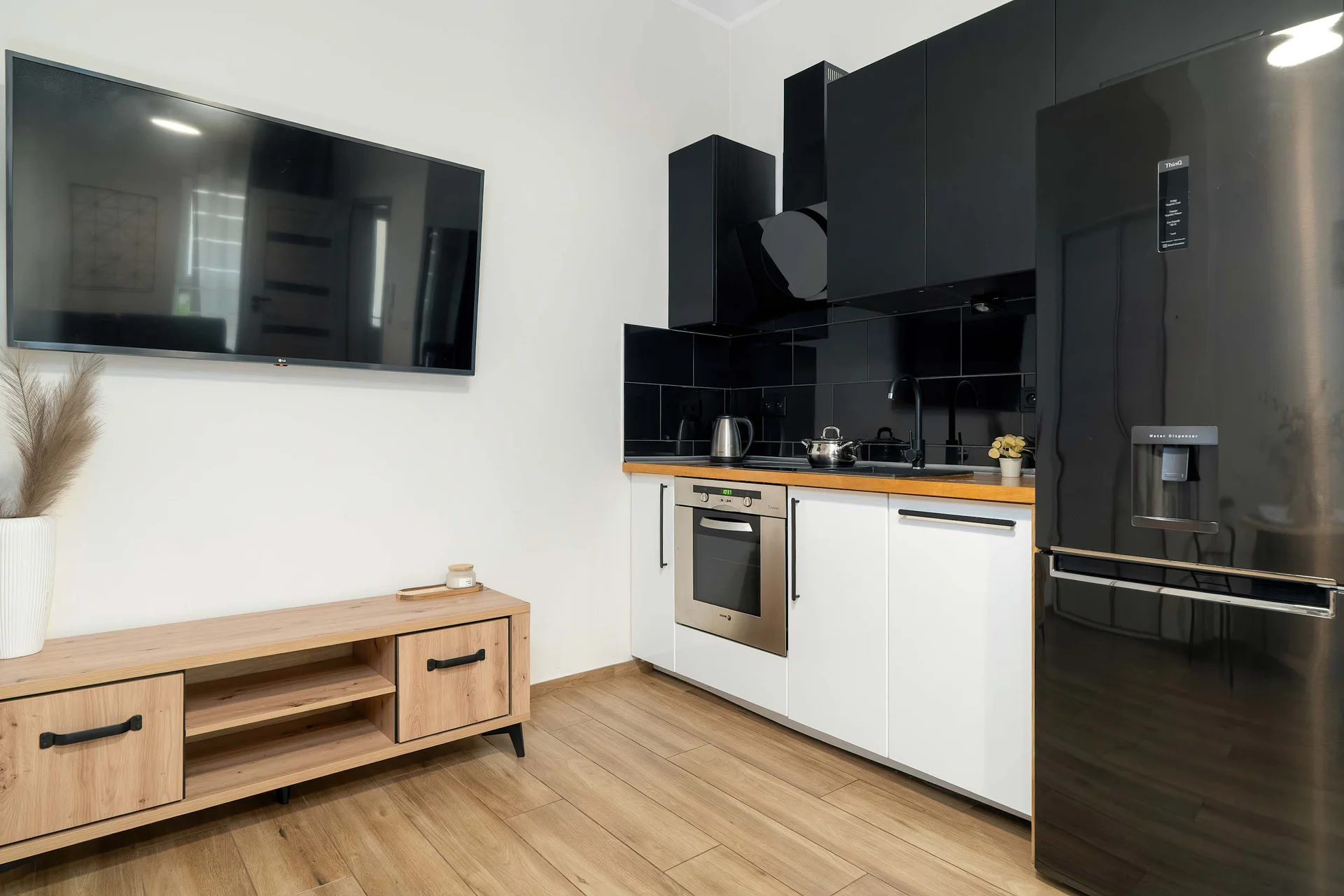 Fully equipped kitchenette with induction hob, oven, efrigerator and modern black and white cabinetry.