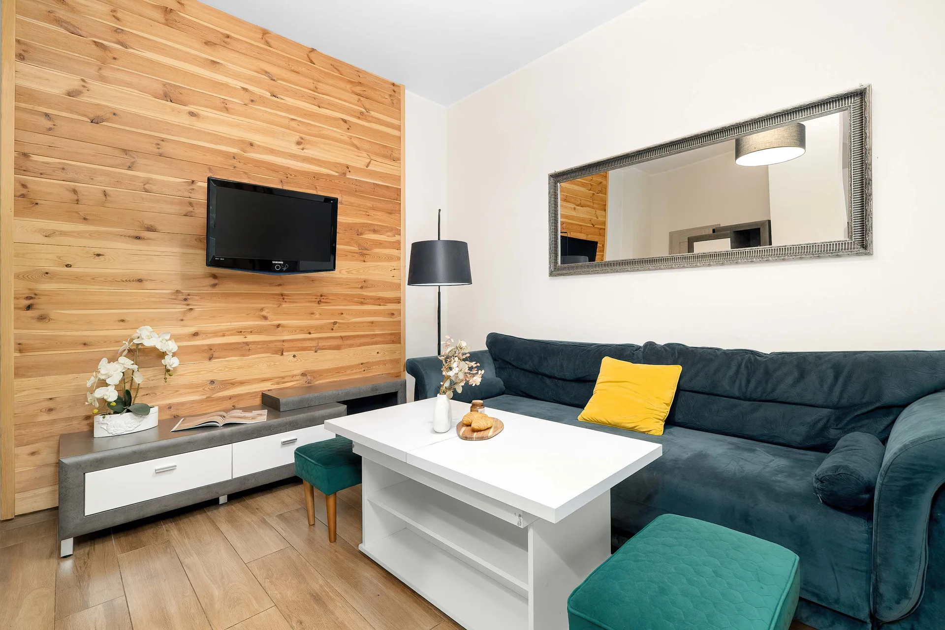 Modern living room with a comfortable sofa, Smart TV, coffee table and elegant wood-accent feature wall.