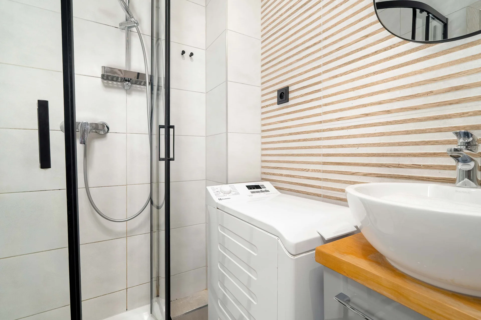 Modern bathroom with a shower, vessel sink, washing machine and elegant wood accents.