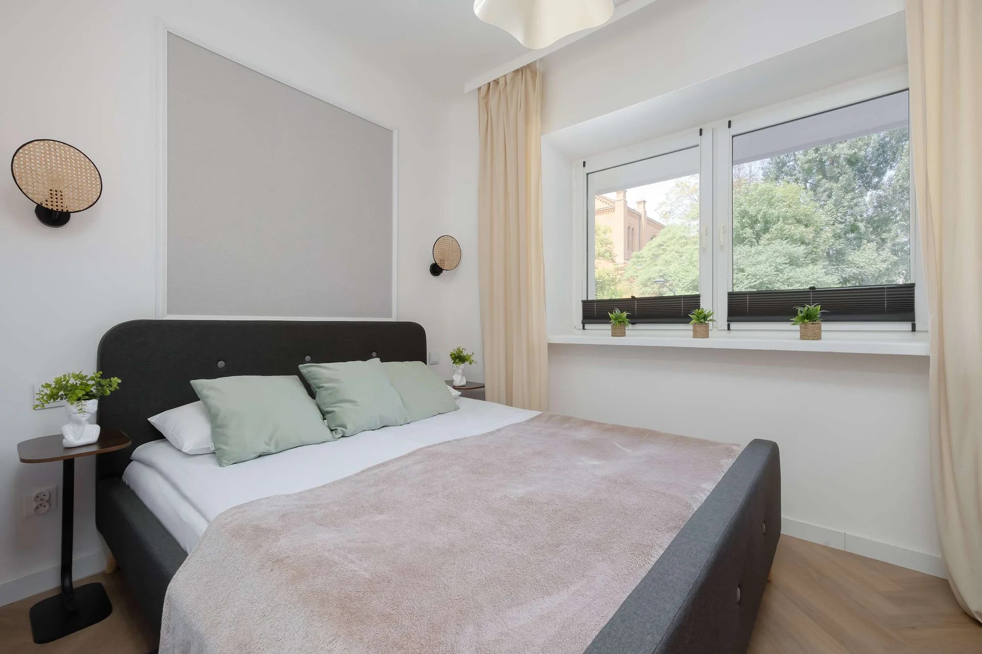 A cozy bedroom with a double bed positioned beside a large window. Natural daylight and simple décor create a relaxing environment.