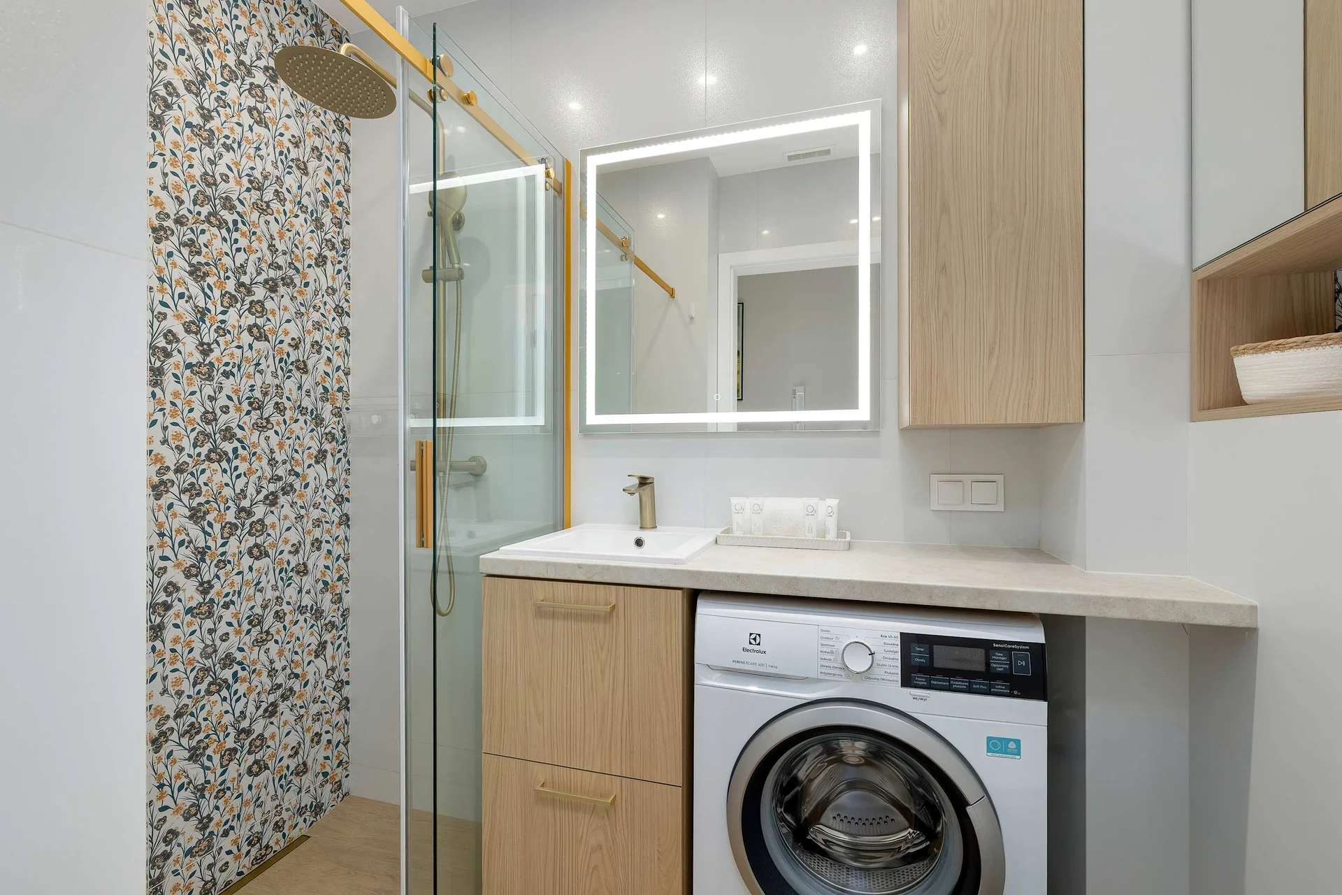 Contemporary bathroom with a walk-in shower, vanity, illuminated mirror, and washing machine.