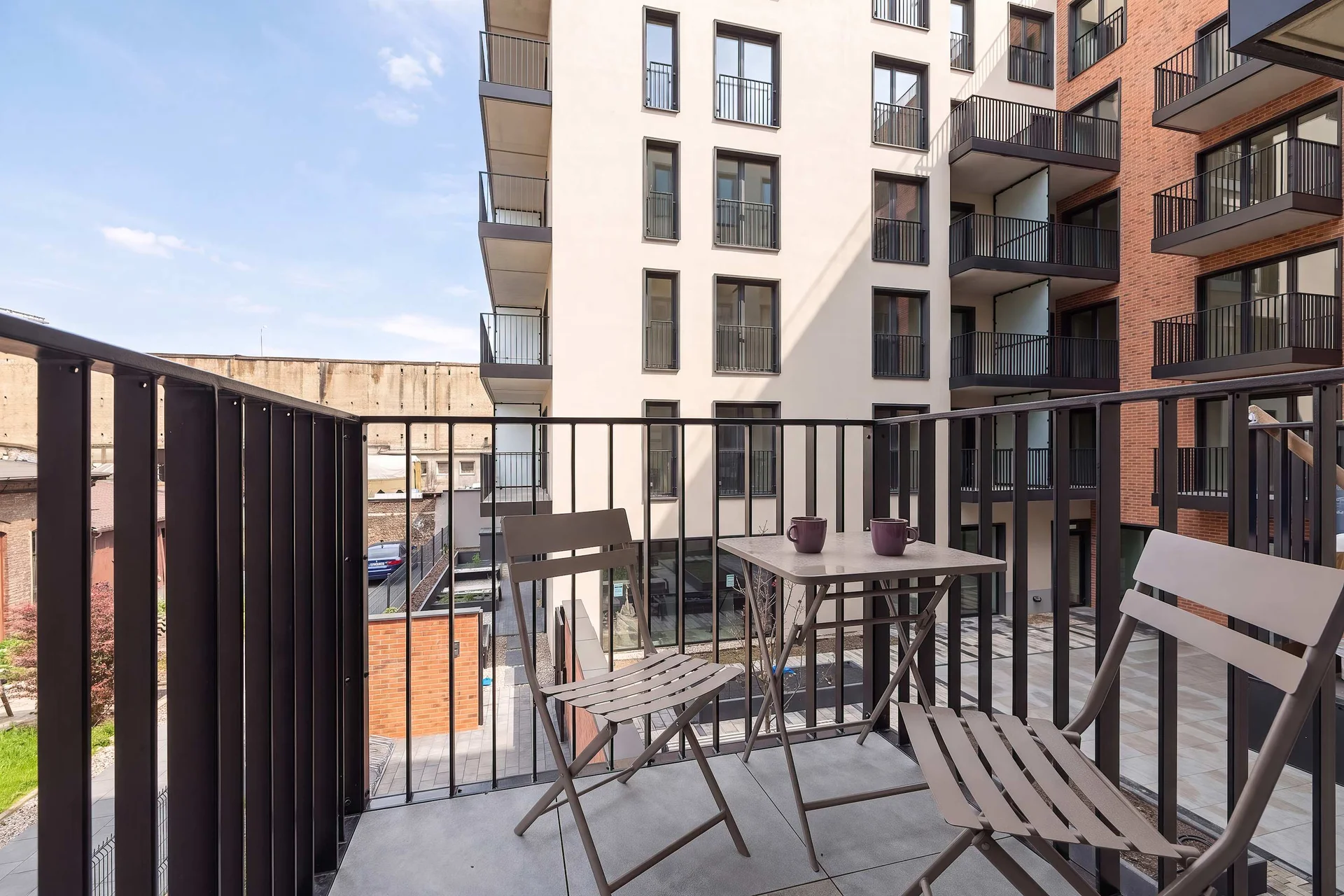 Private balcony with outdoor seating overlooking the modern residential complex.