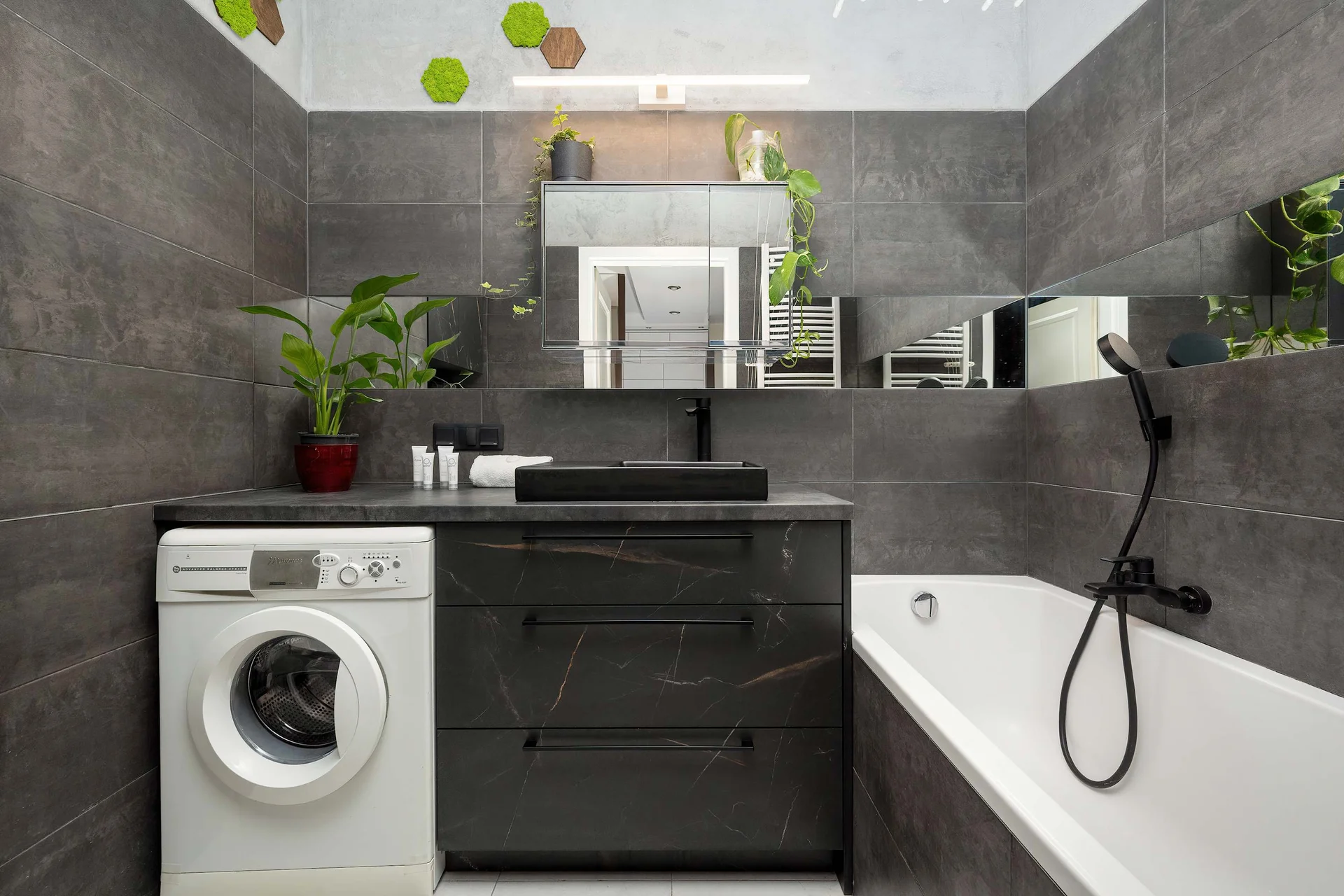 Contemporary bathroom with a bathtub, washing machine, vanity, and modern finishes.