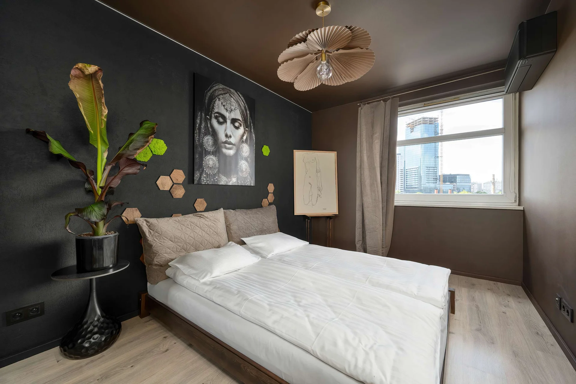 Stylish bedroom with a comfortable double bed, elegant wall art, and a large window filling the room with natural light.