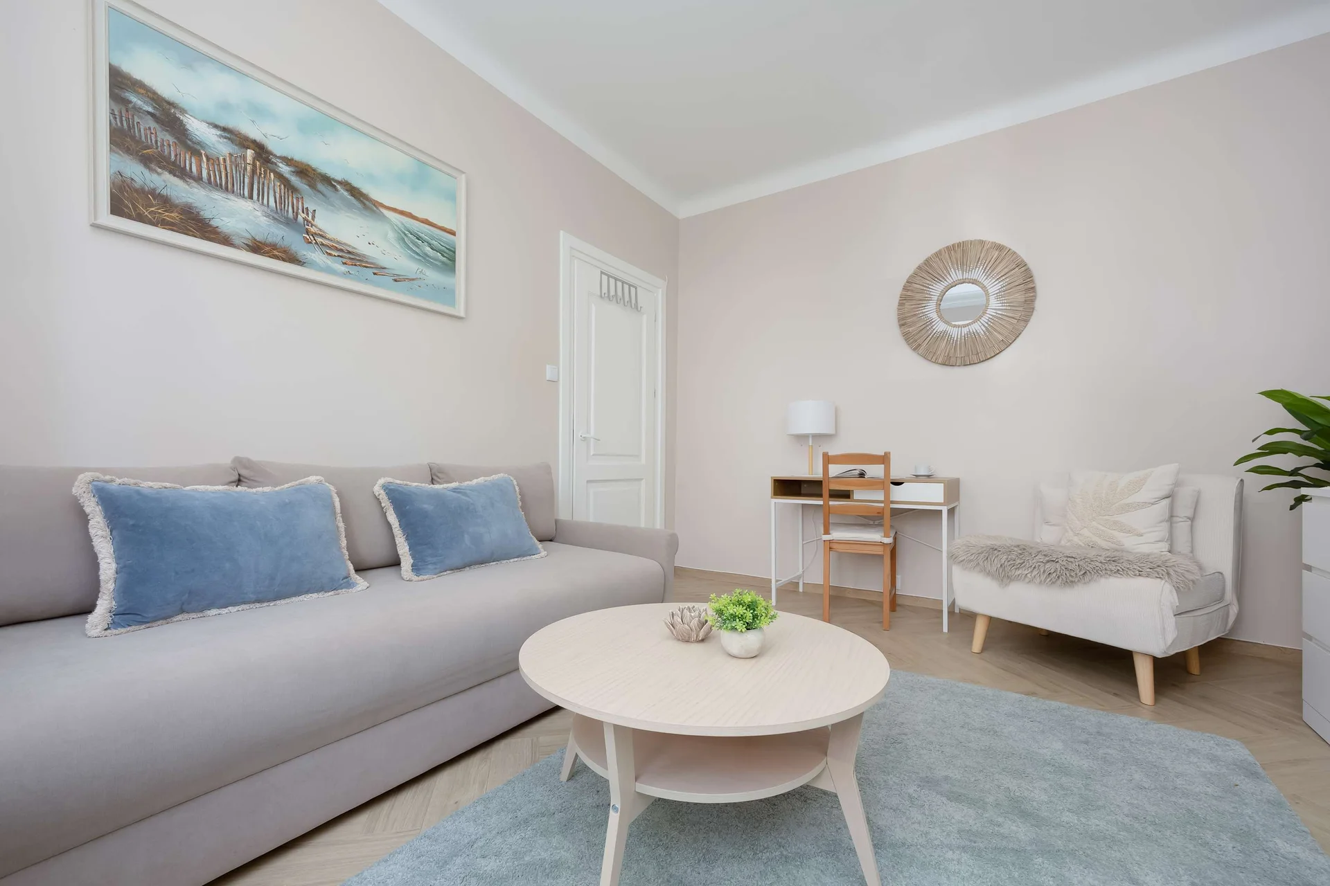 An alternative photo of the sleeping area showcases the sofa set against a light grey wall decorated with artwork. The layout creates an inviting spot both for sleeping and loungig.