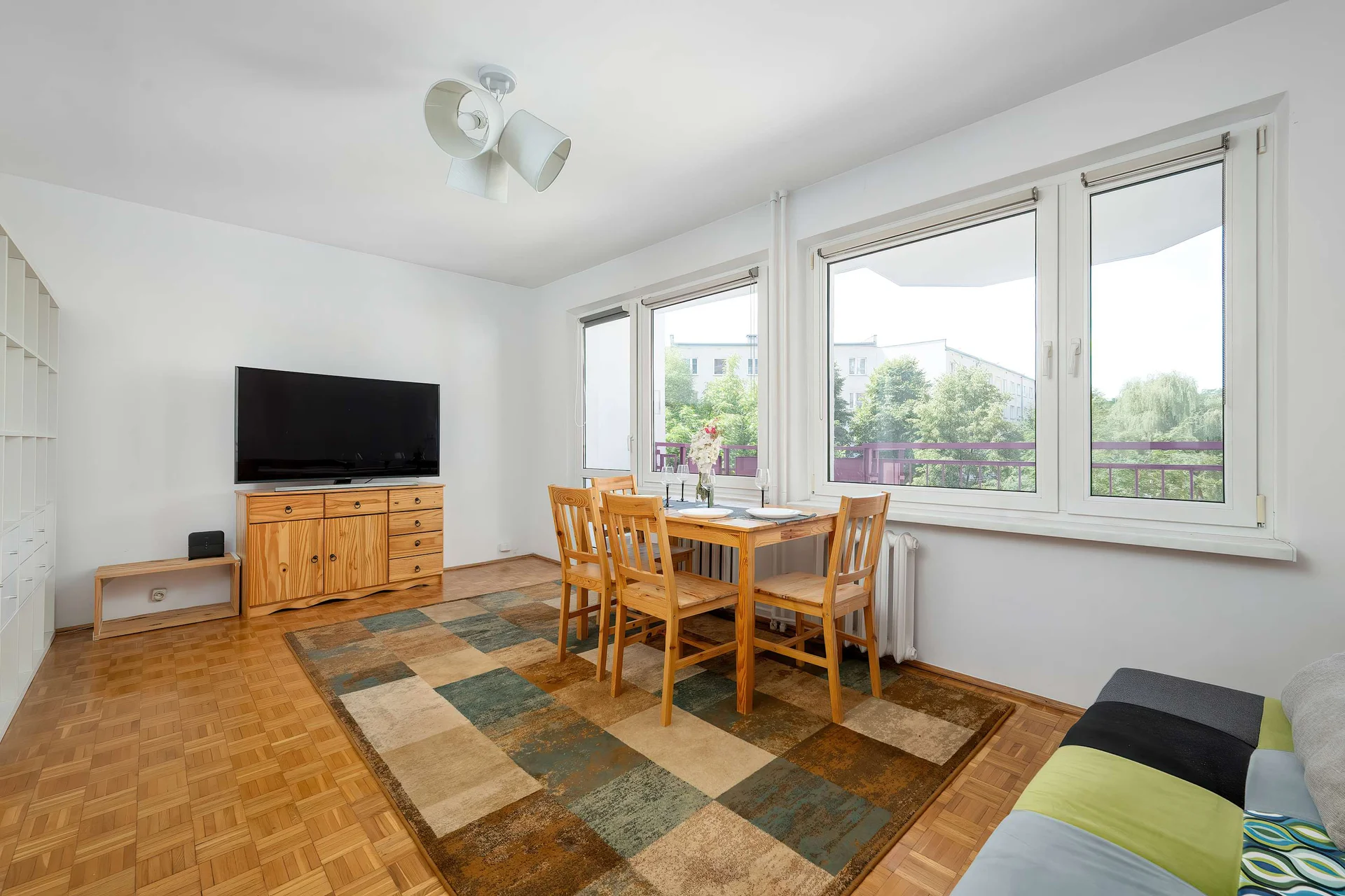 Bright bedroom with a dining table, TV, comfortable seating, and large windows letting in plenty of natural light.