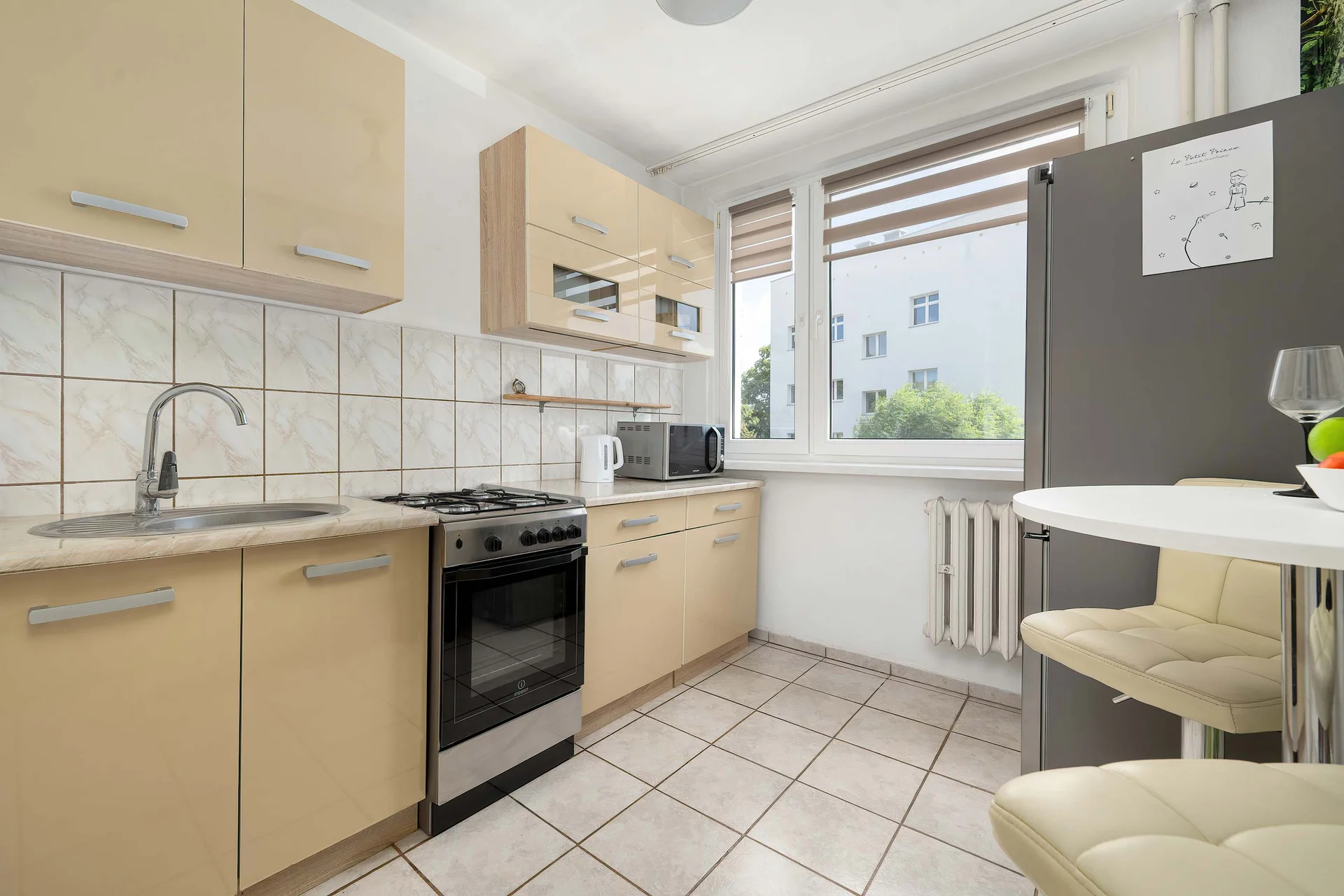 Fully equipped separate kitchen with wooden cabinets, a gas stove, oven, refrigerator, and dining space.