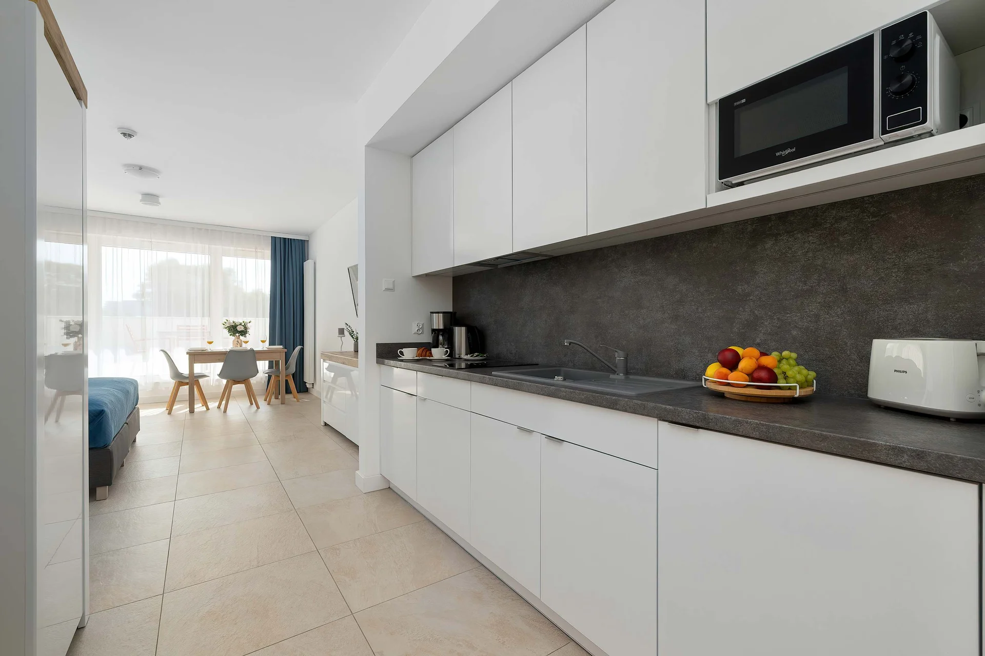 A close view of the stylish kitchen area featuring elegant white cabinetry and a spacious countertop. The minimalist design provides a clean and comfortable cooking environment.