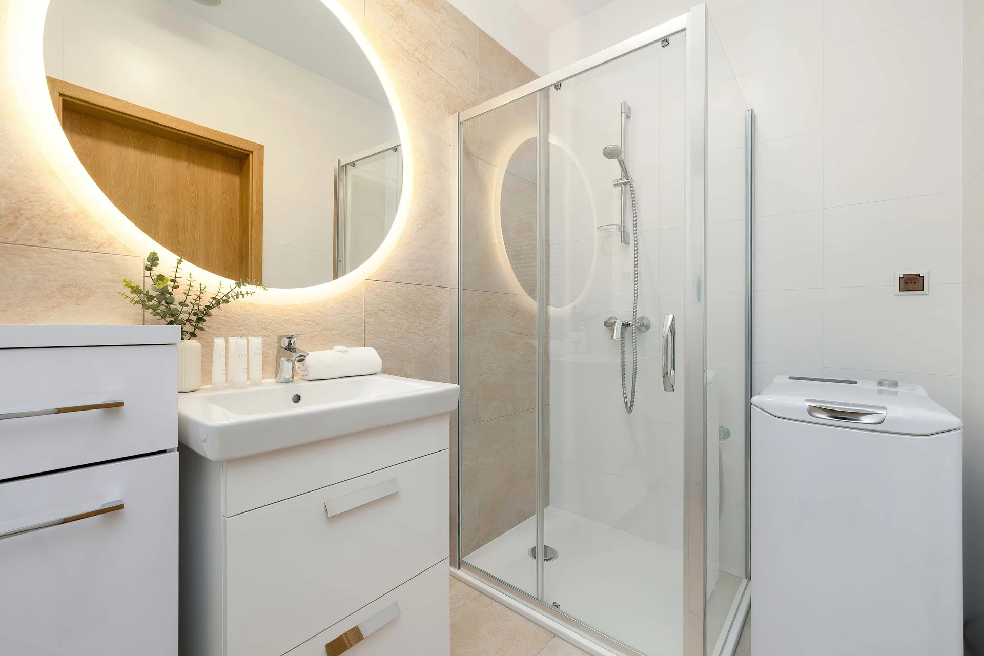 A bright bathroom with a large mirror, sink area, and modern shower. The neutral colors create a calm and elegant atmosphere.