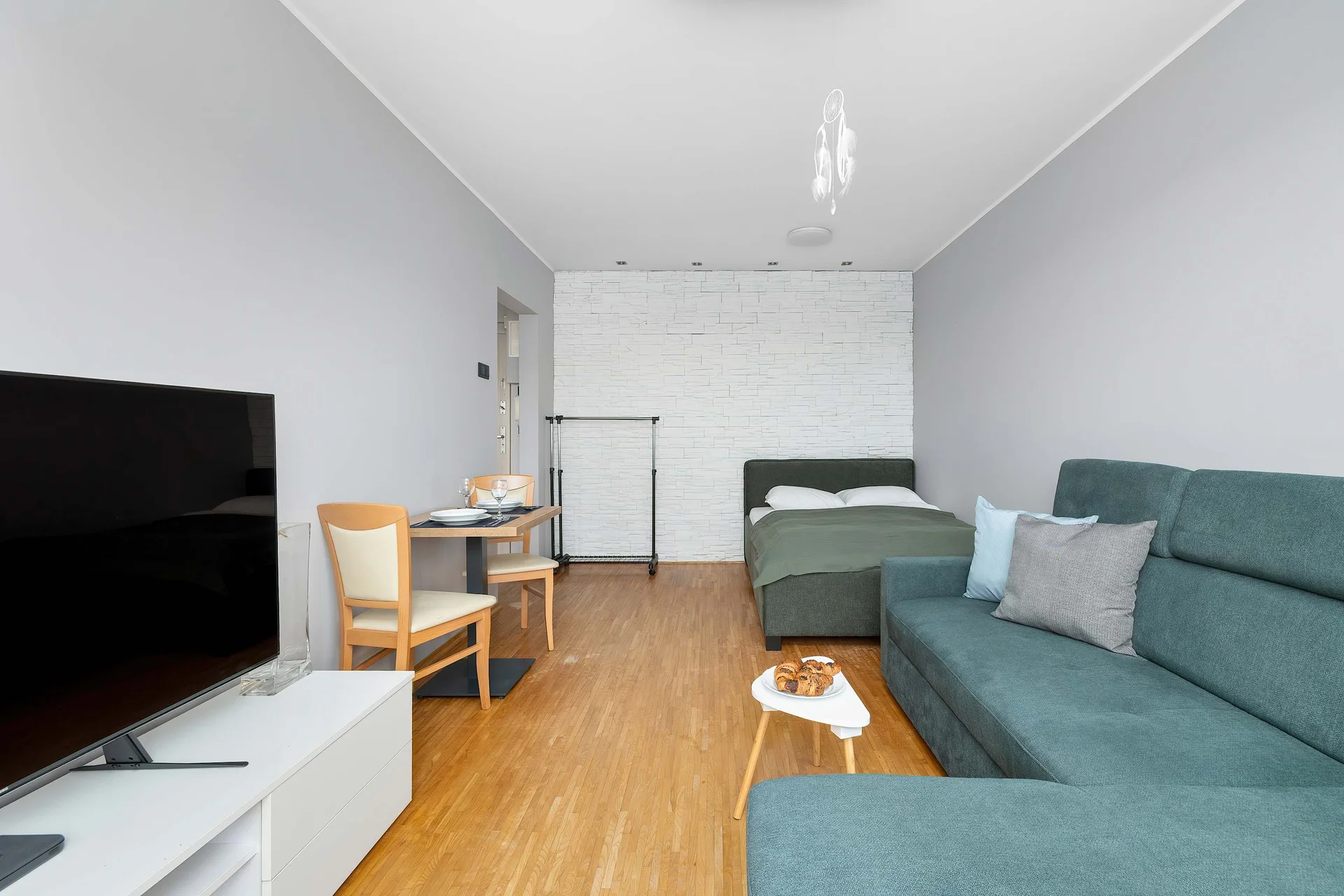 A cozy living area with a sofa, TV, and compact kitchenette. The bright interior creates a welcoming atmosphere.