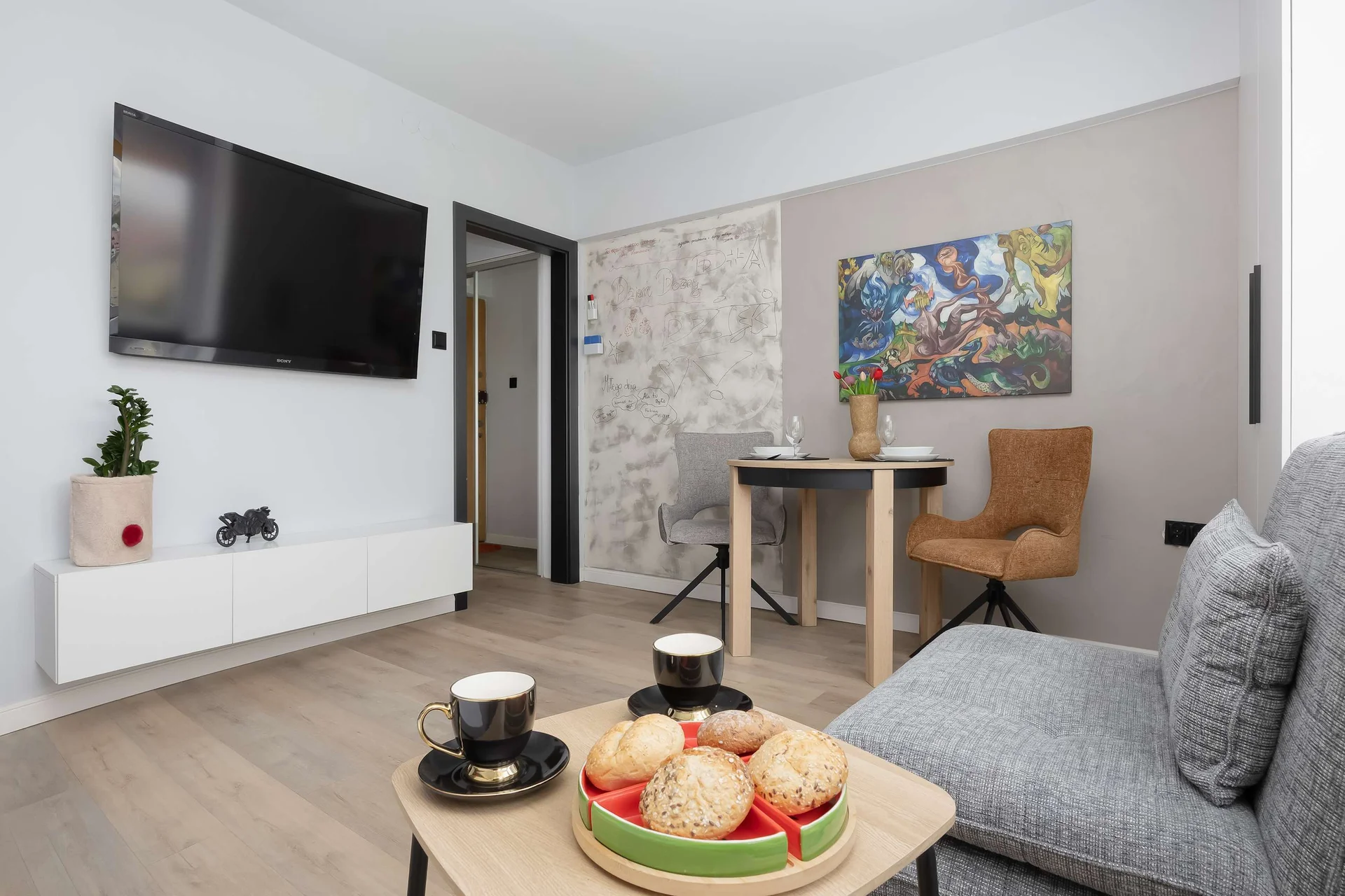 Comfortable living area with a single sofa bed, wall-mounted TV, dining table, and modern décor.