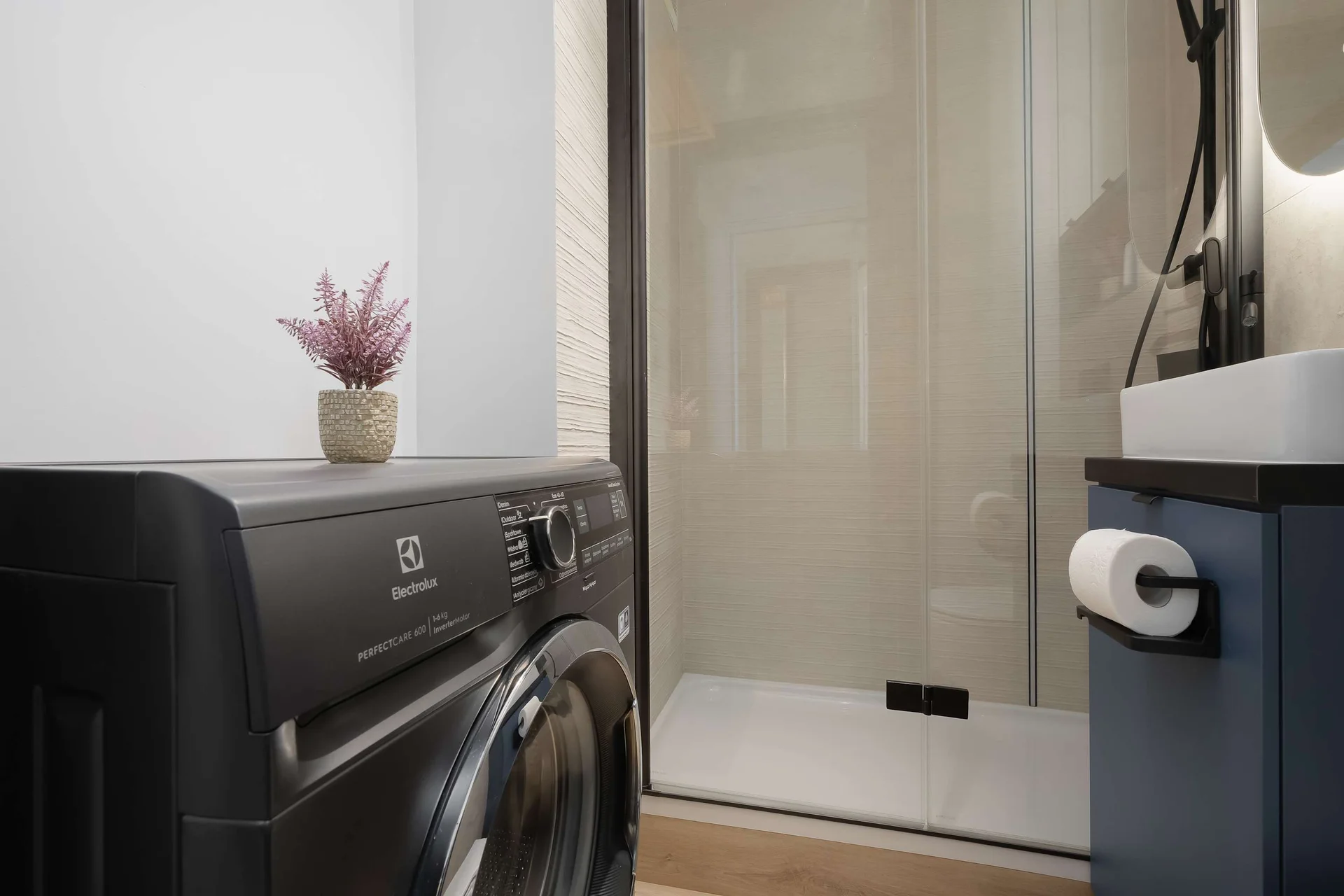 Contemporary bathroom with a shower, washing machine, toilet, and modern finishes.