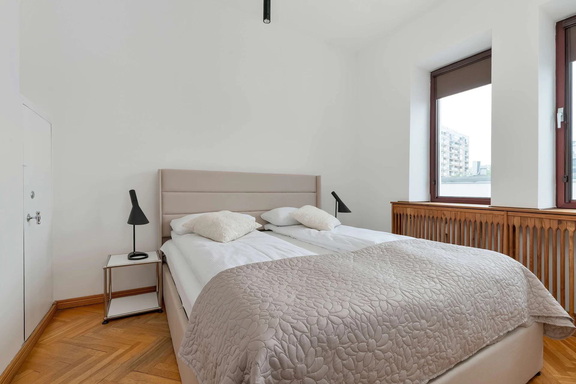 A comfortable bedroom with a double bed and soft bedding offers a peaceful place to relax. Natural light brightens the minimalistic interior.
