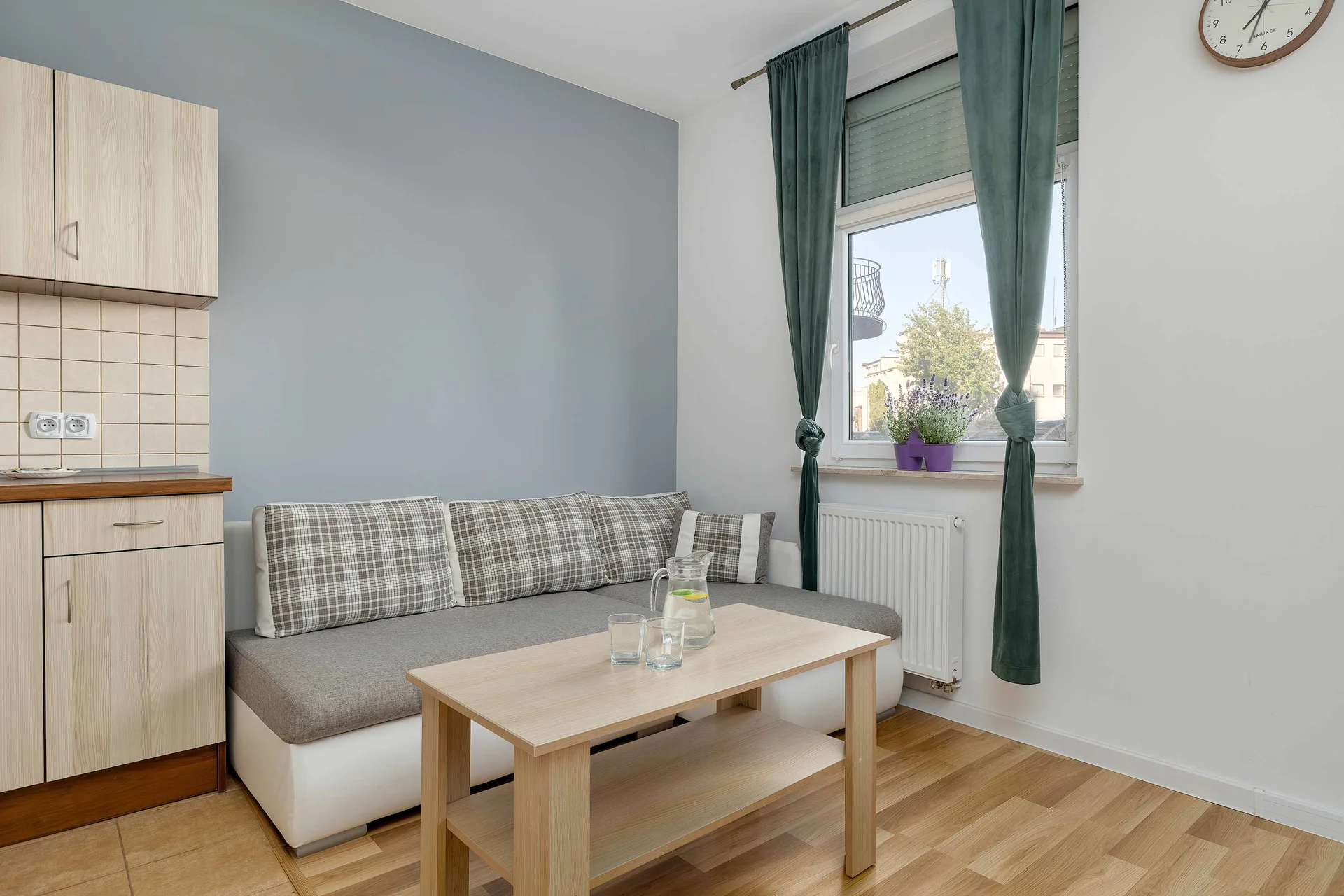 Modern studio space featuring a comfortable sofa, dining table, and a fully equipped kitchenette.