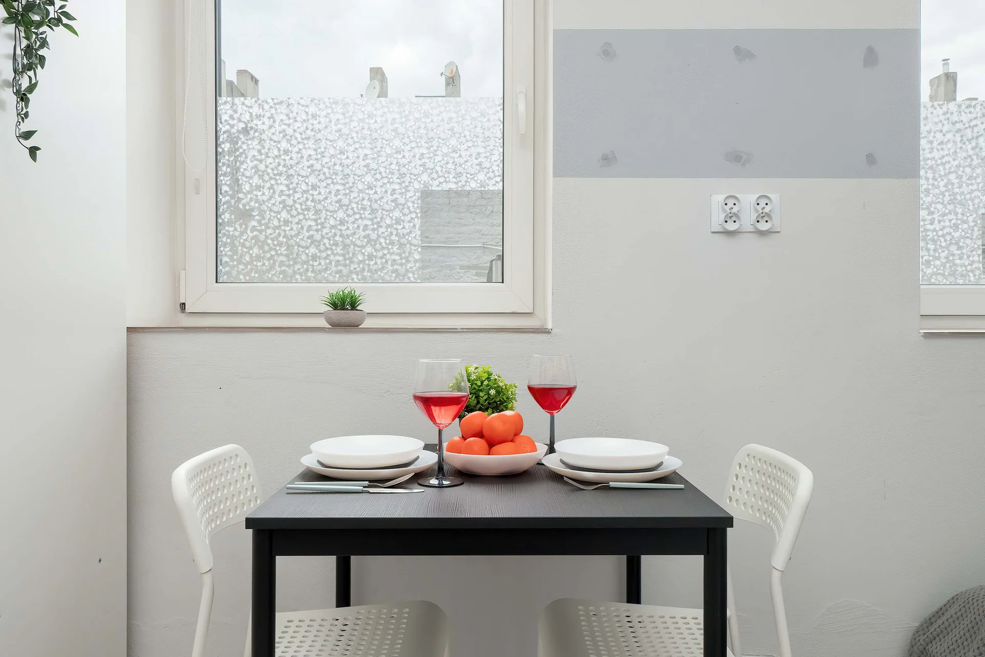 A dining area with a table and chairs next to a bright window. It offers a pleasant space for meals or coffee.