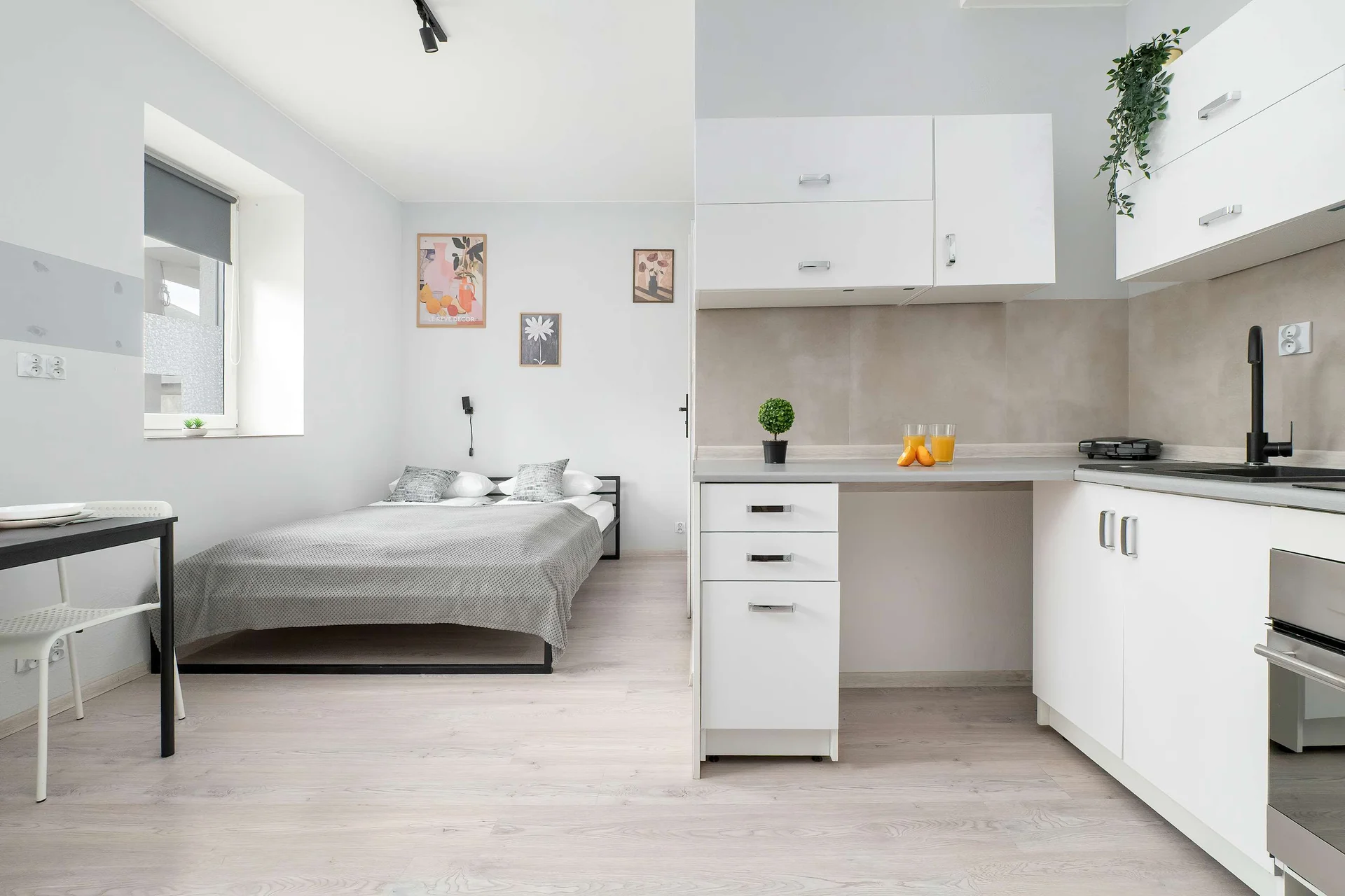 A bright studio with a double bed and a fully equipped kitchenette. Large windows make the space feel airy and inviting.