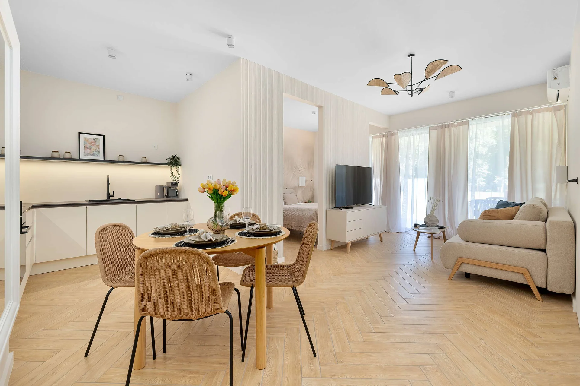 The open-plan dining area connects seamlessly with the living room and kitchen, creating a spacious and inviting layout. Large windows brighten the entire interior.