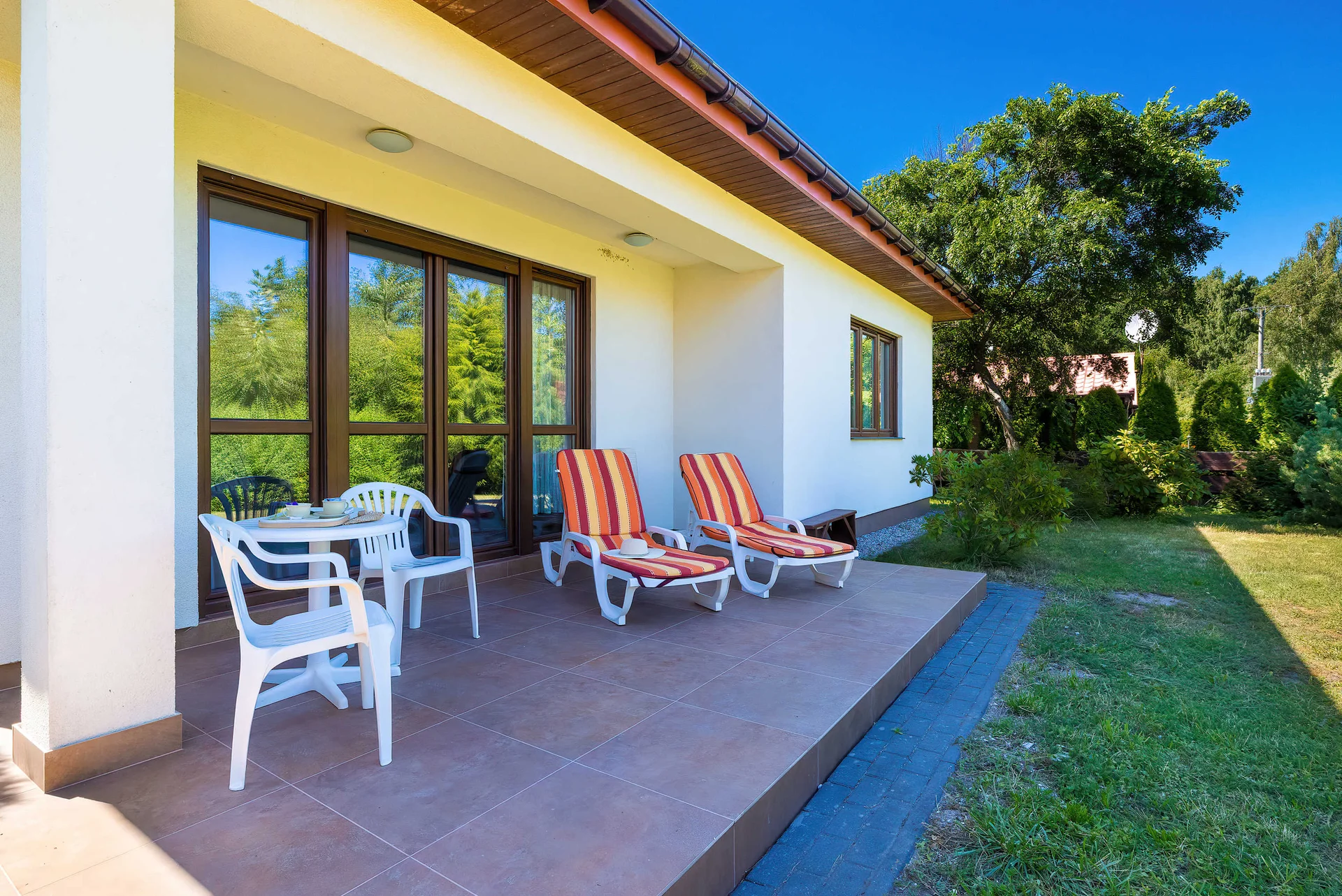 A covered terrace with outdoor seating and sun loungers overlooking the garden. It offers a pleasant space to relax outside.