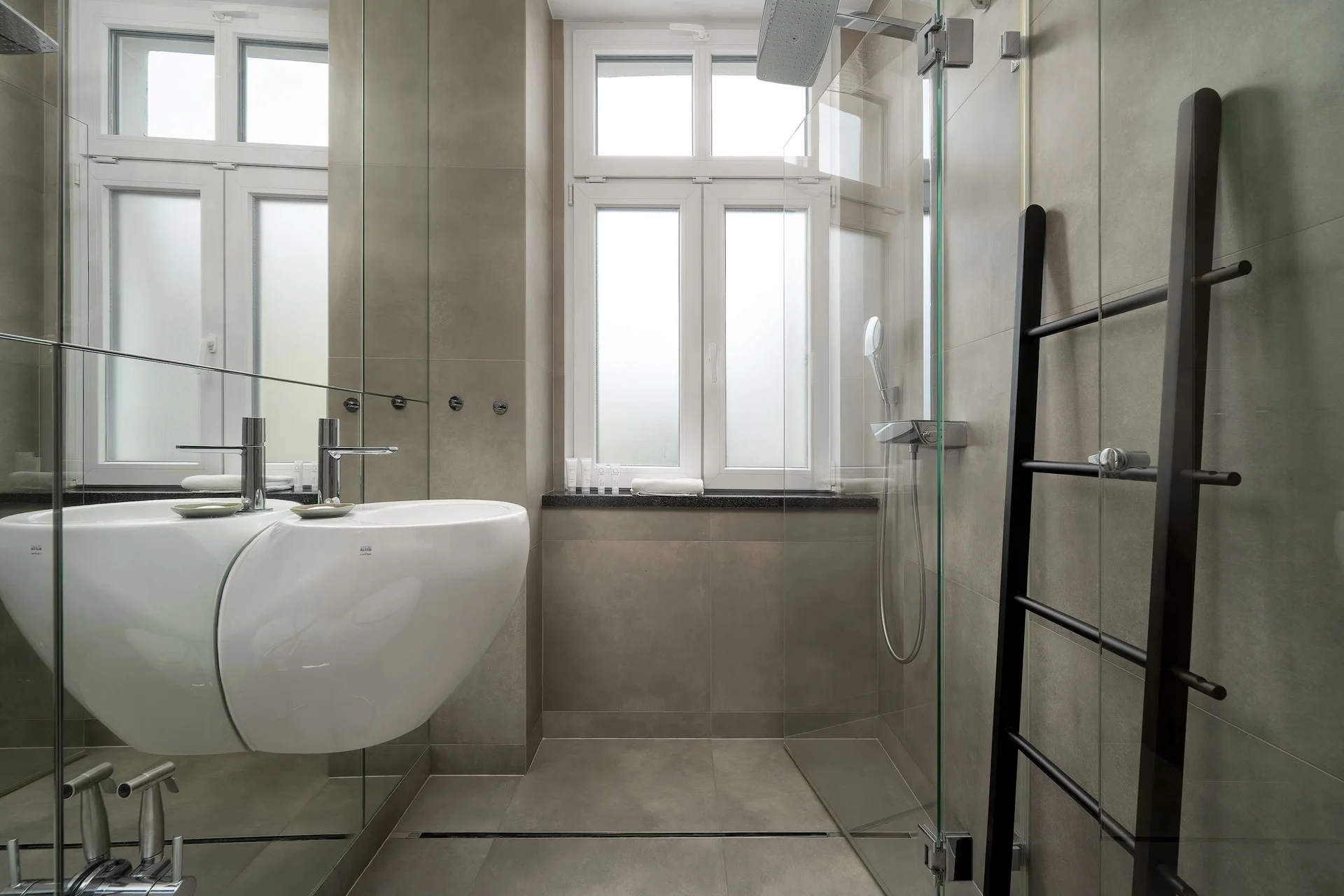 Elegant bathroom with a walk-in shower, modern fittings, and large windows bringing in natural light.