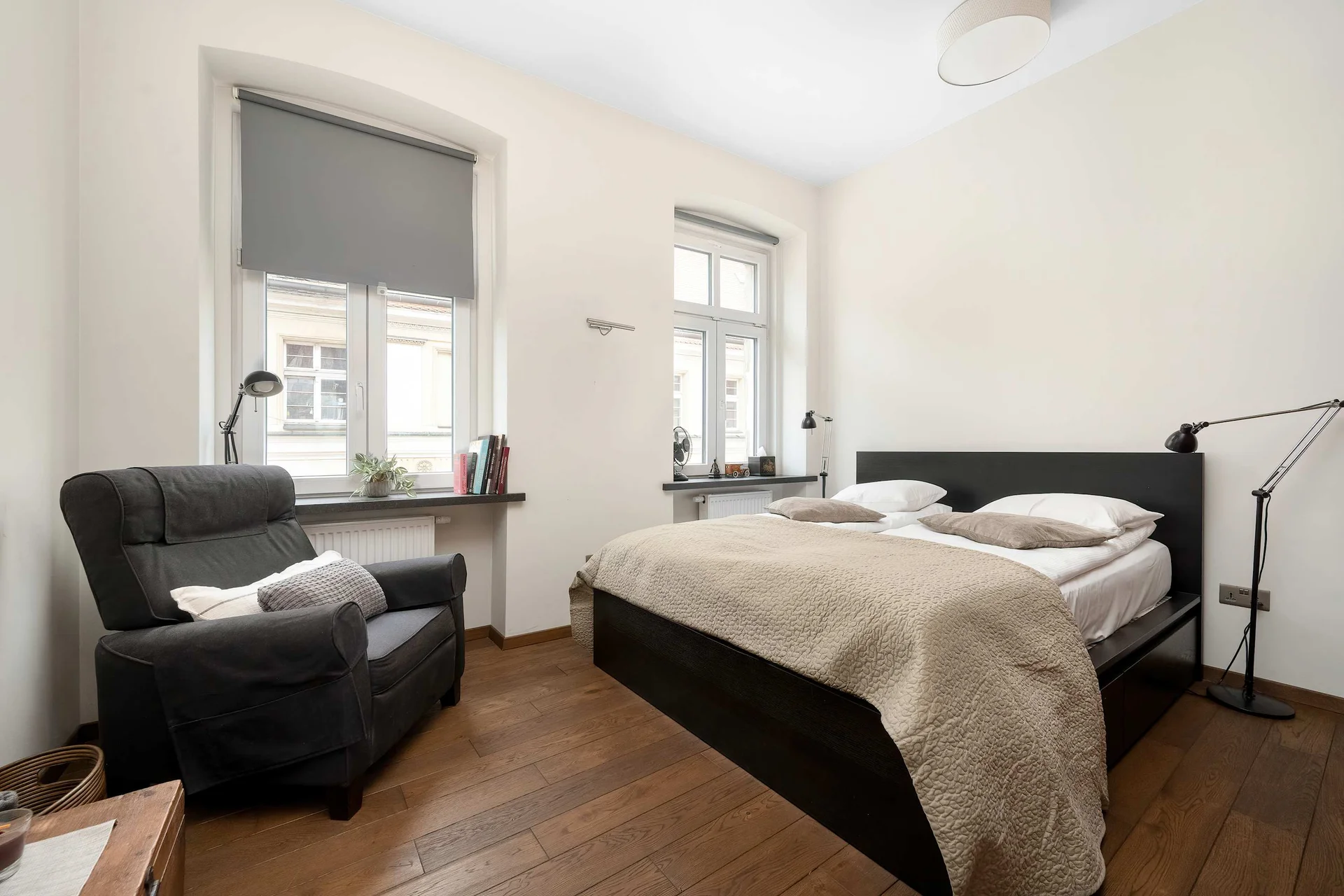 Cozy bedroom featuring a double bed, an armchair by the window, and minimalist décor.
