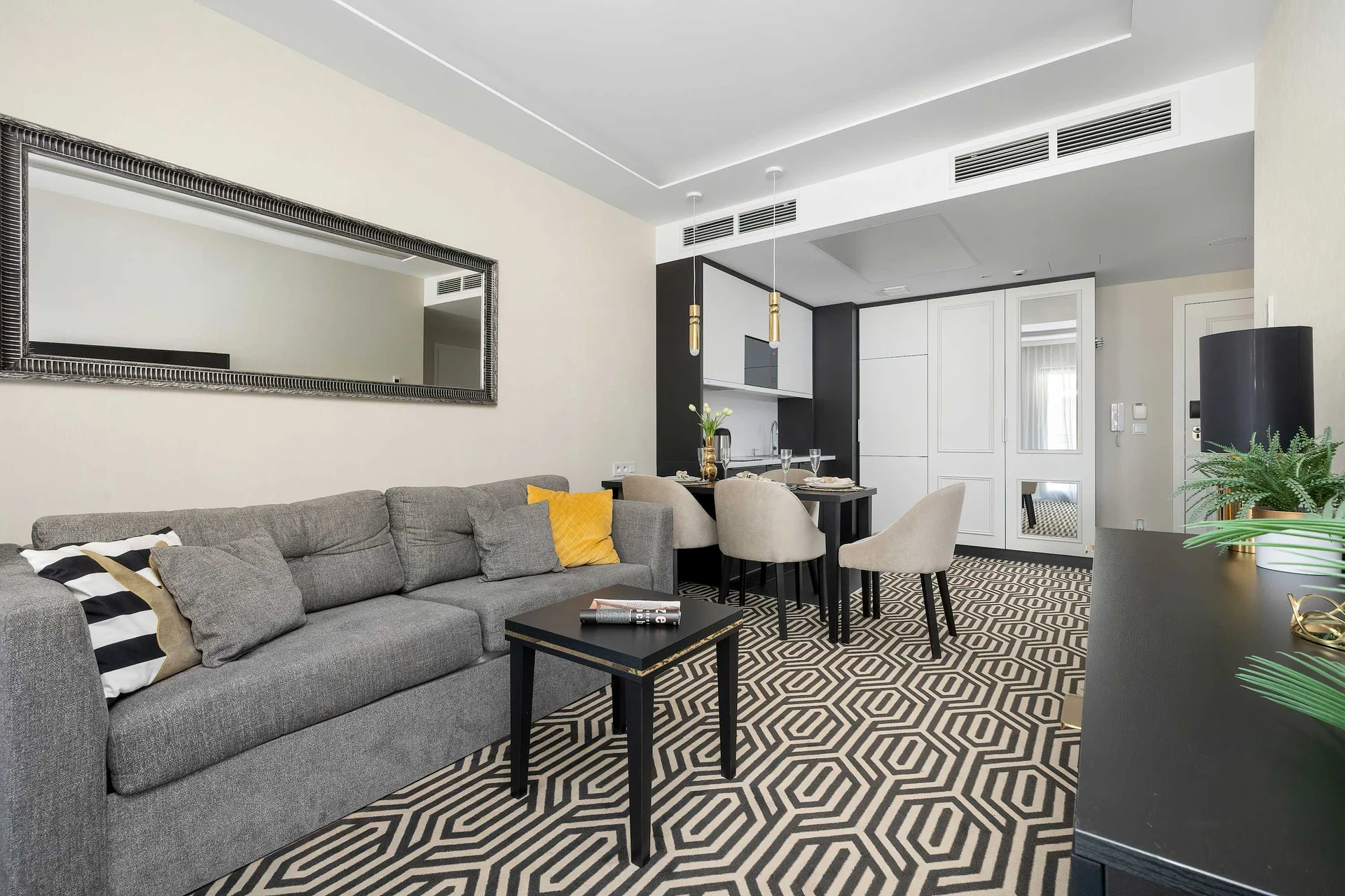The living room is arranged around a comfortable gray sofa facing a large wall-mounted television. Clean lines and stylish décor create an inviting place to unwind.