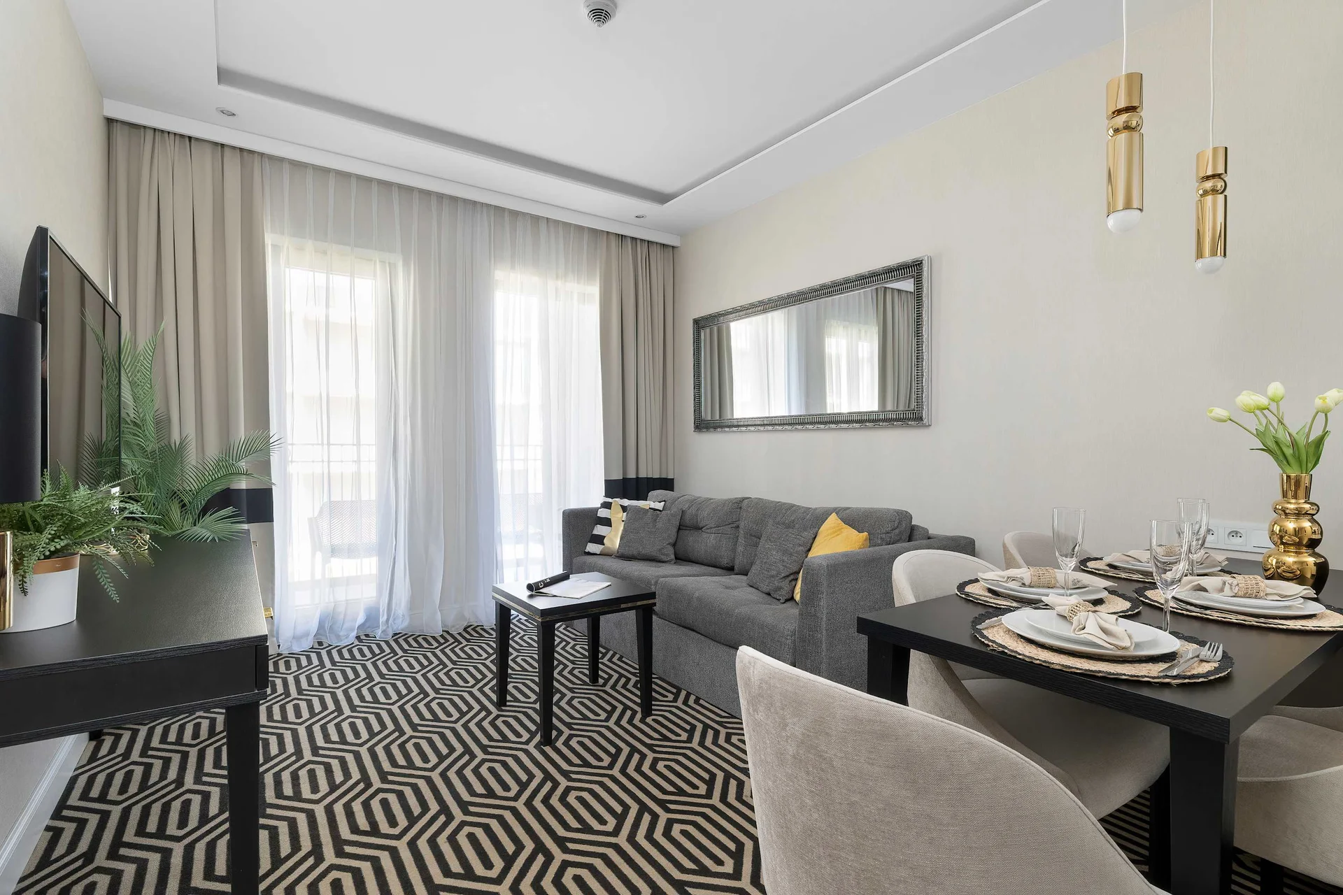 The open-plan living area includes a comfortable sofa, dining table, and decorative lighting. Contemporary furnishings give the apartment a refined and welcoming feel.