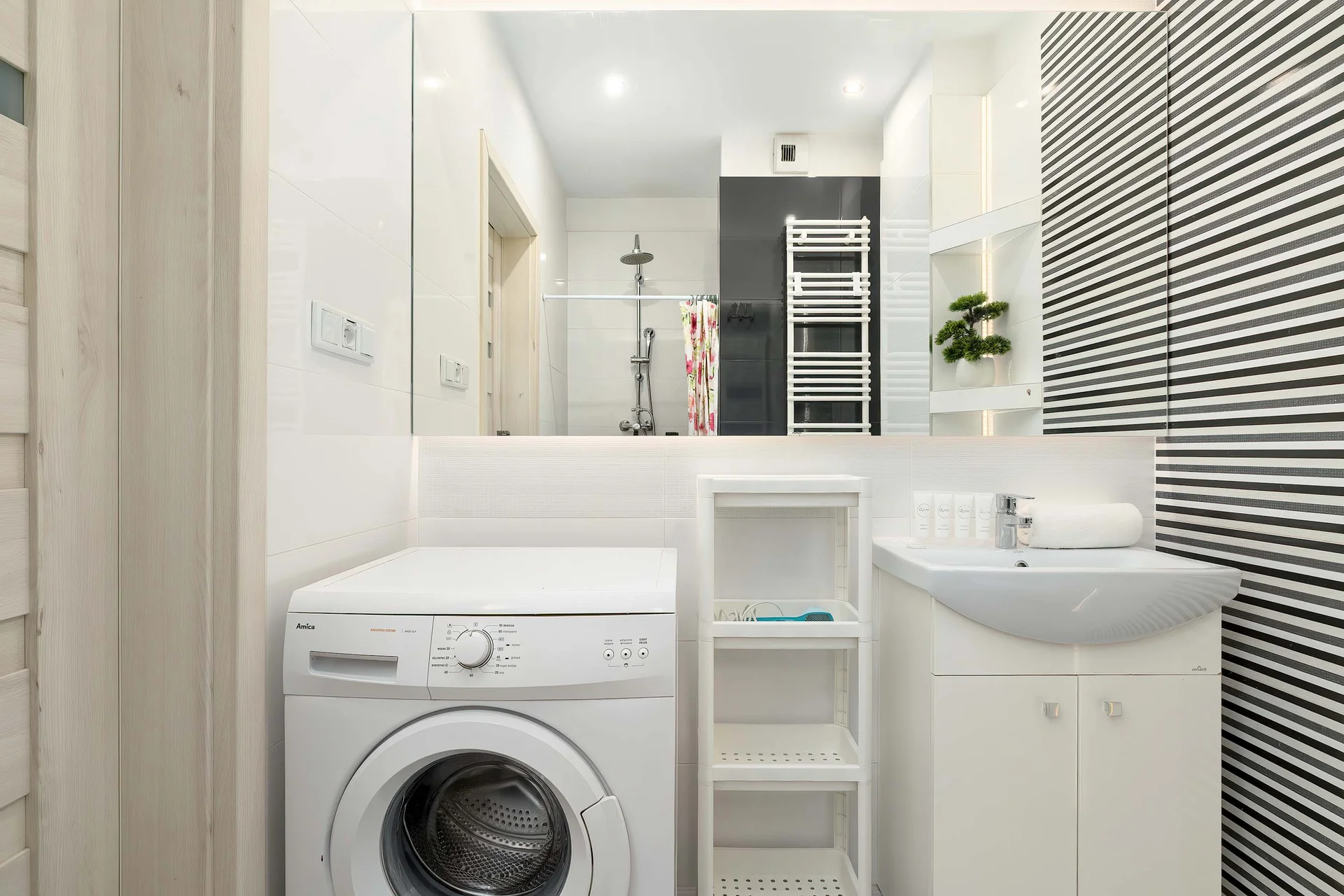 A clean and modern bathroom with a shower, washing machine, and plenty of storage space. Everything you need for a comfortable stay is at your fingertips.