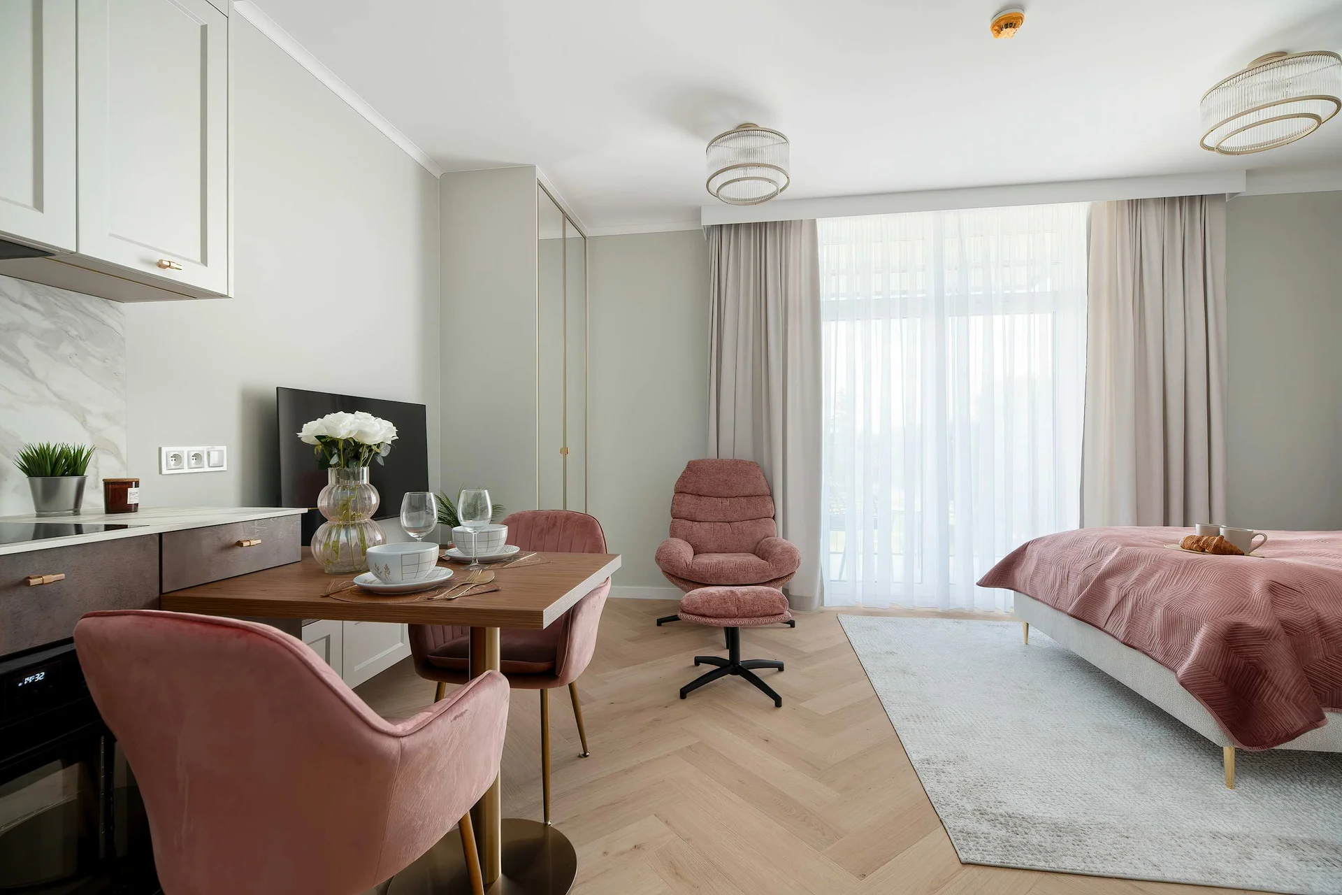 A spacious studio with a double bed, kitchenette, and dining area. Large windows make the room bright and inviting.