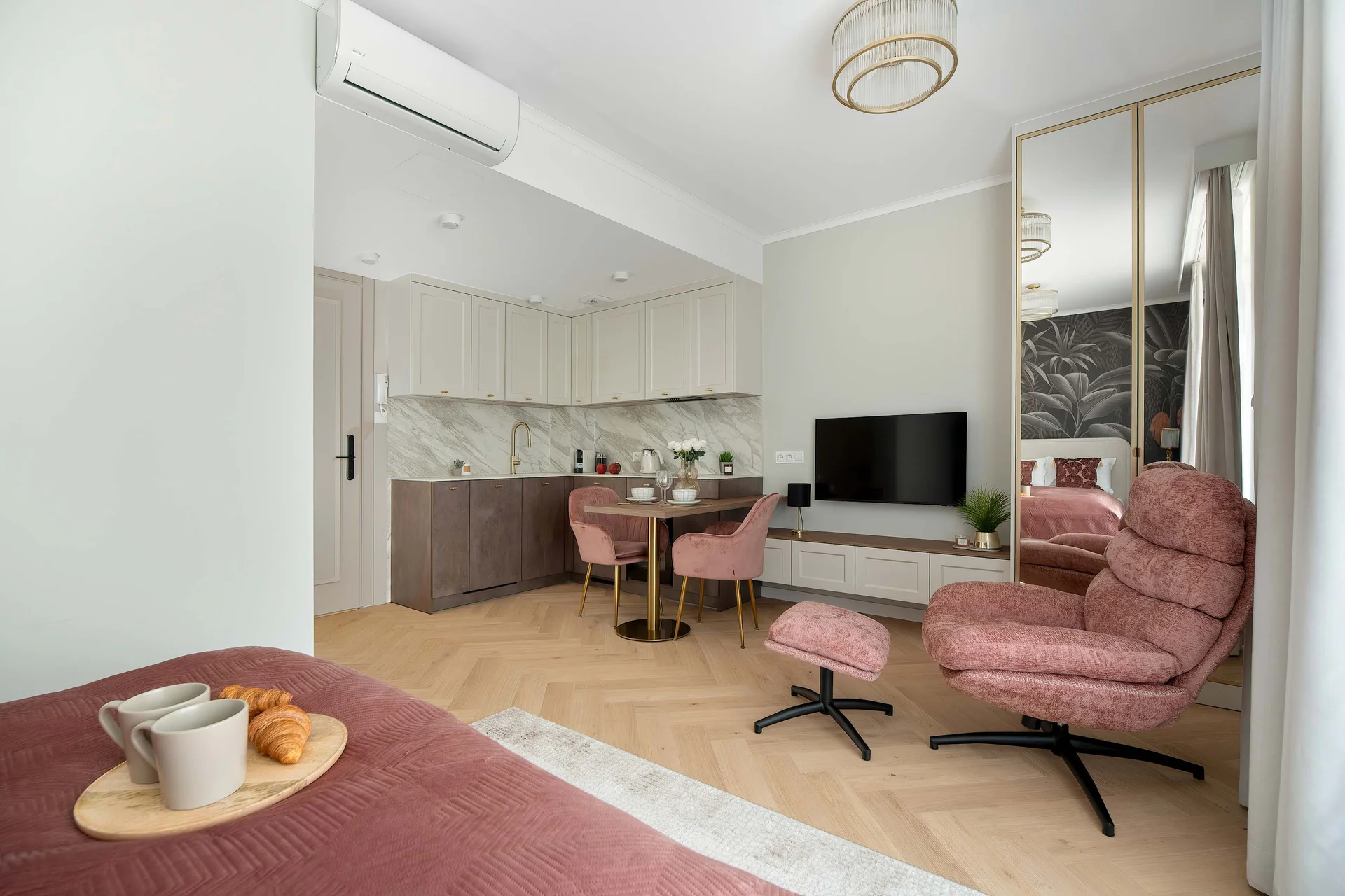 An open-plan living area with a kitchenette, dining table, and comfortable seating. The space is bright and modern.