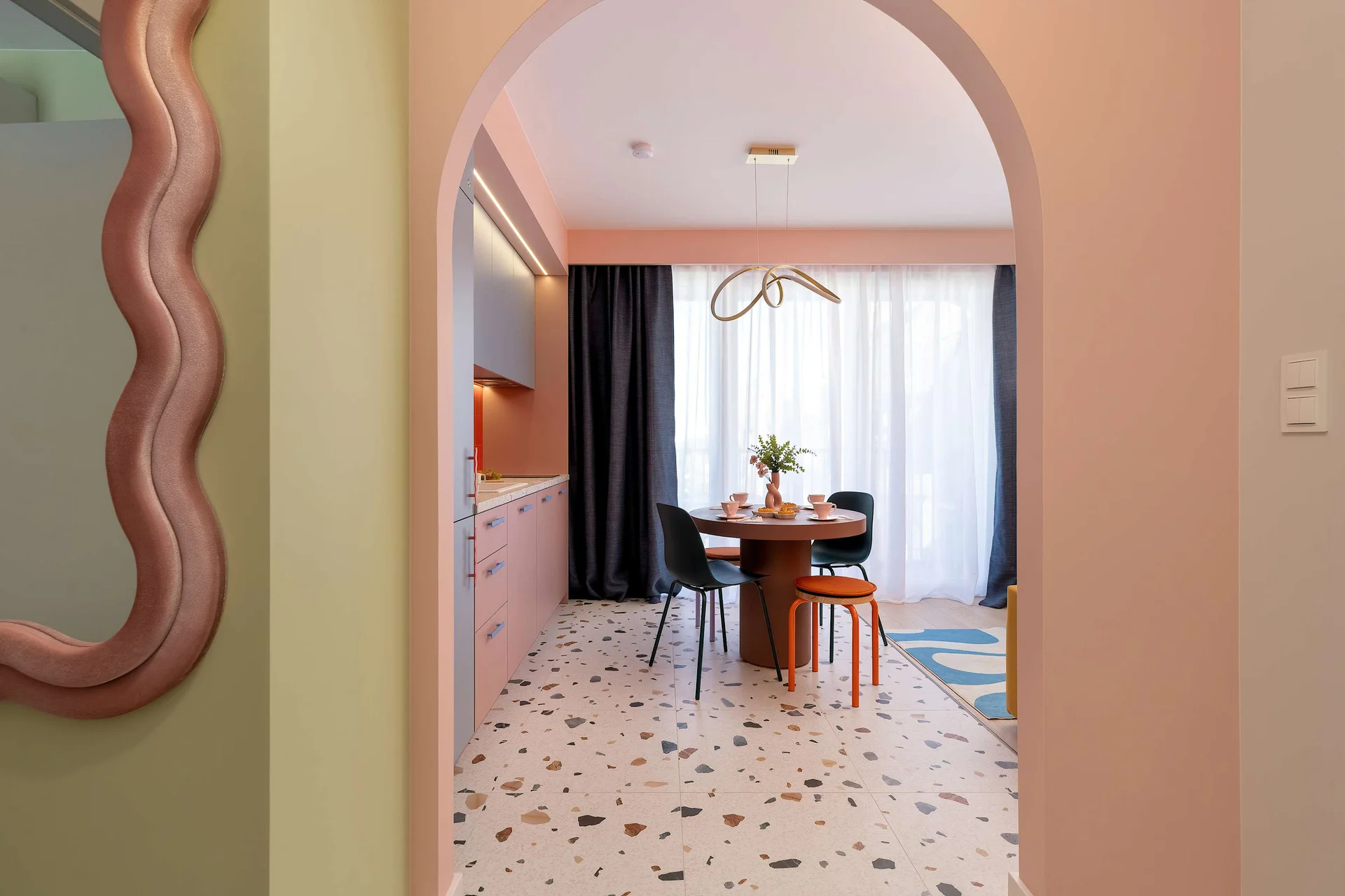 A bright interior with an arched doorway, decorative mirror, and dining area in the background.