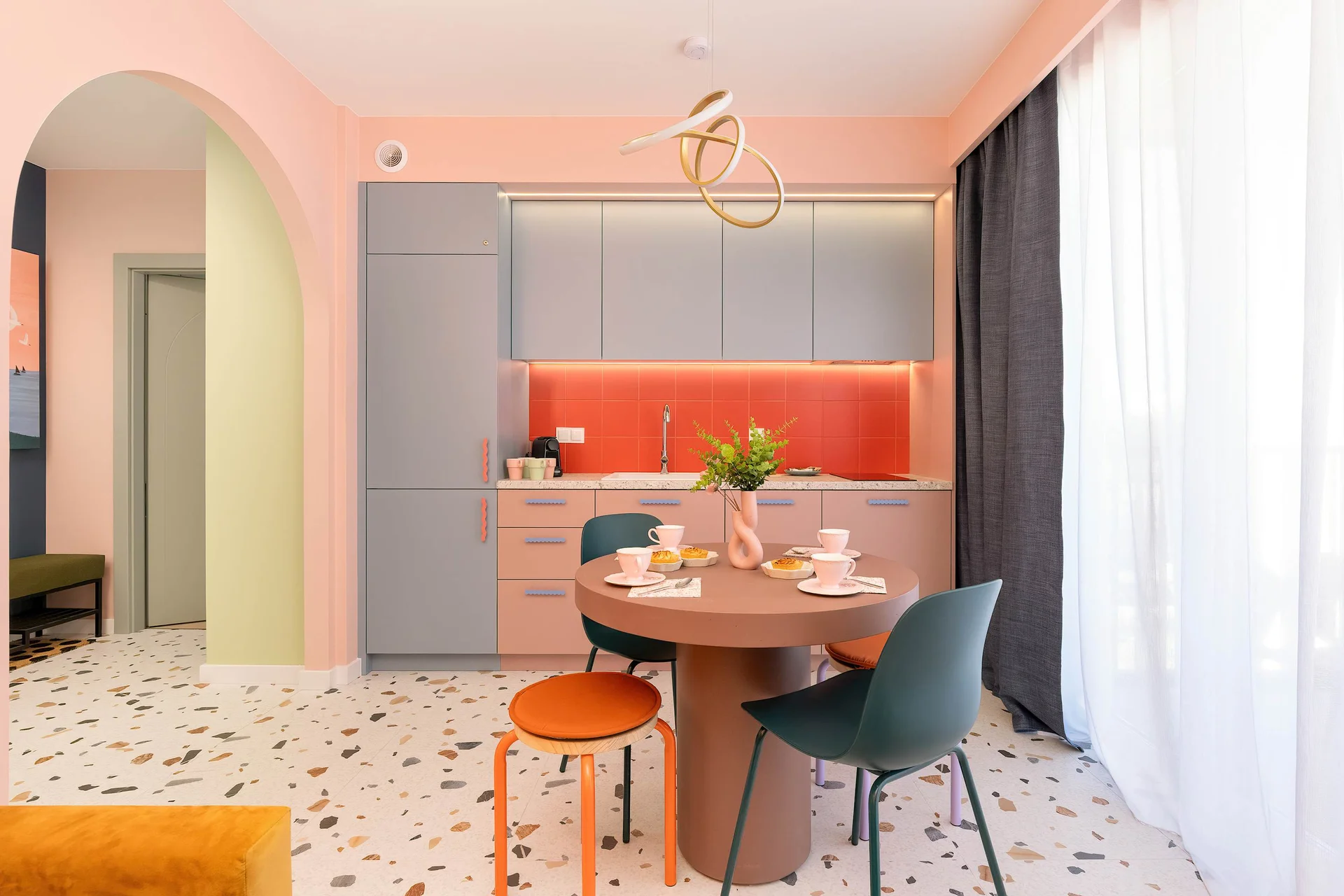 A stylish dining area with a round table, dark chairs, and warm orange accents.