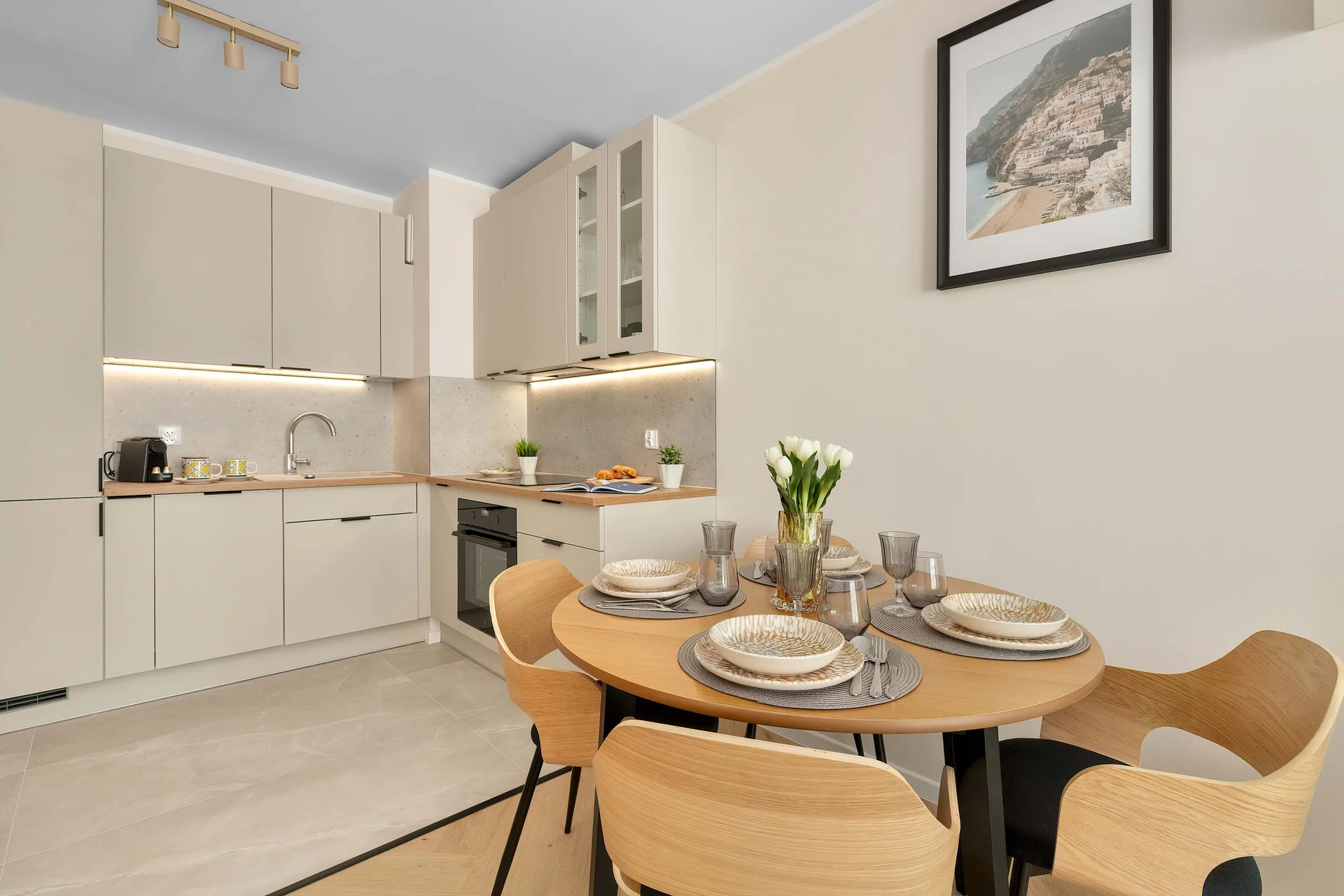 Modern kitchenette with cabinets, integrated appliances and a small dining area.