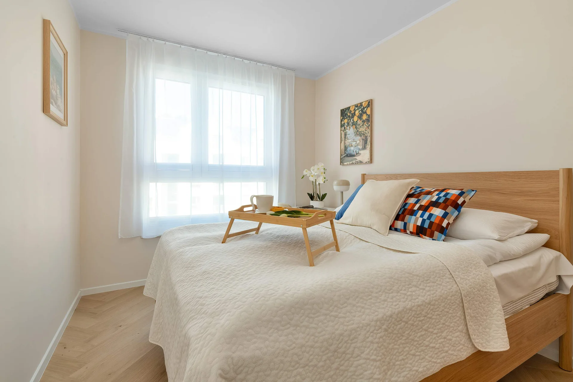 Bright and comfortable bedroom with a double bed, wooden headboard and a large window.