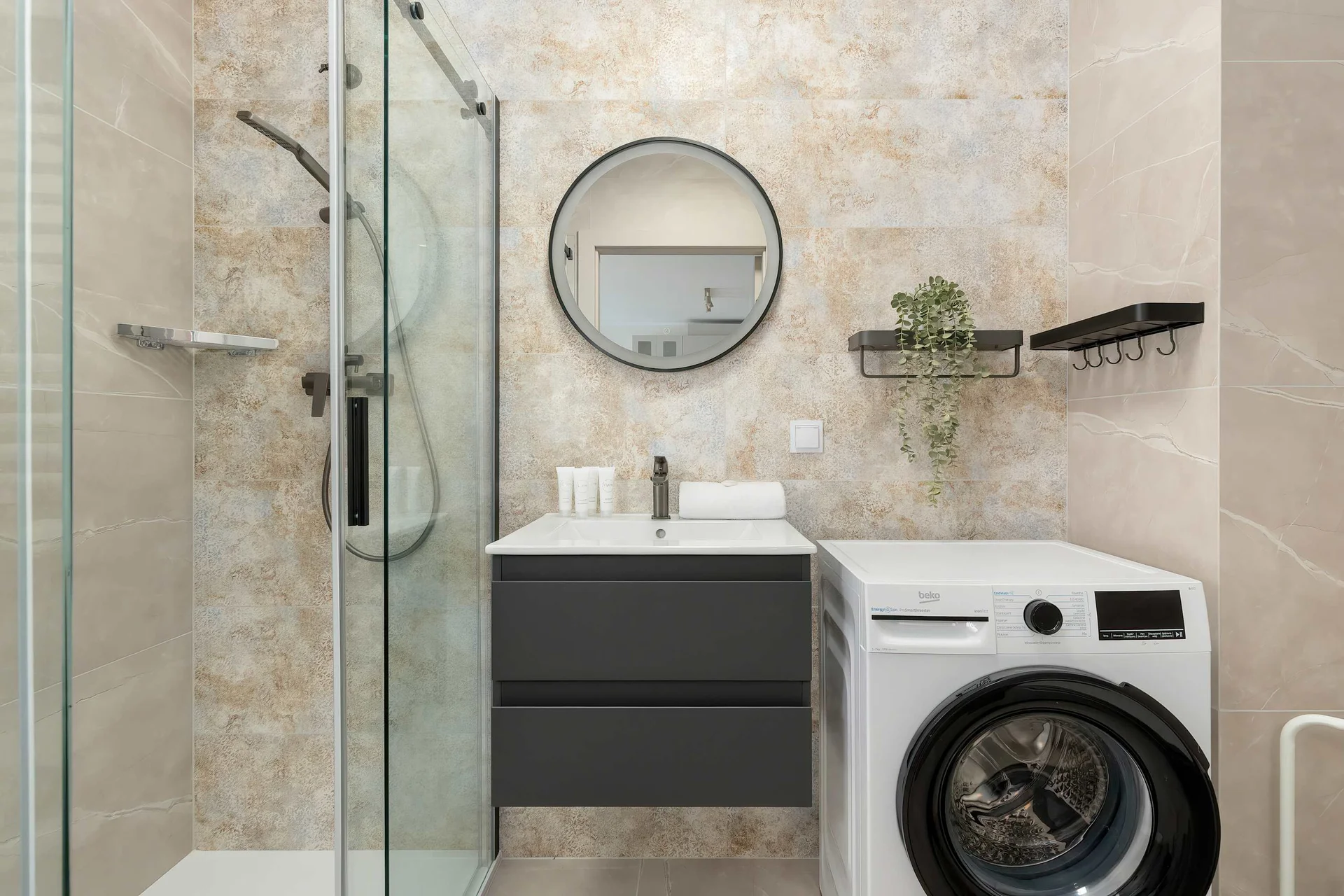 Modern bathroom with shower, washing machine, wall-mounted sink and contemporary fixtures.