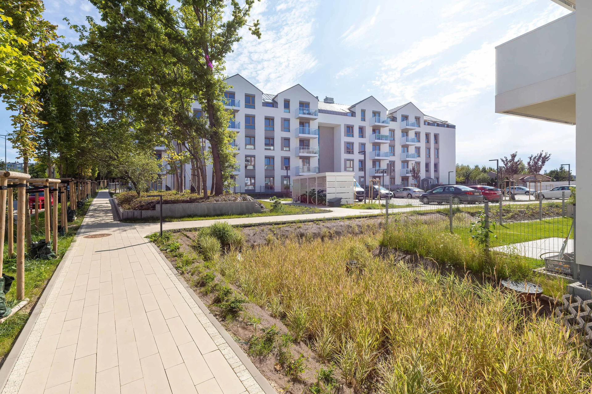 Modern residential building surrounded by landscaped green areas and pedestrian walkways.