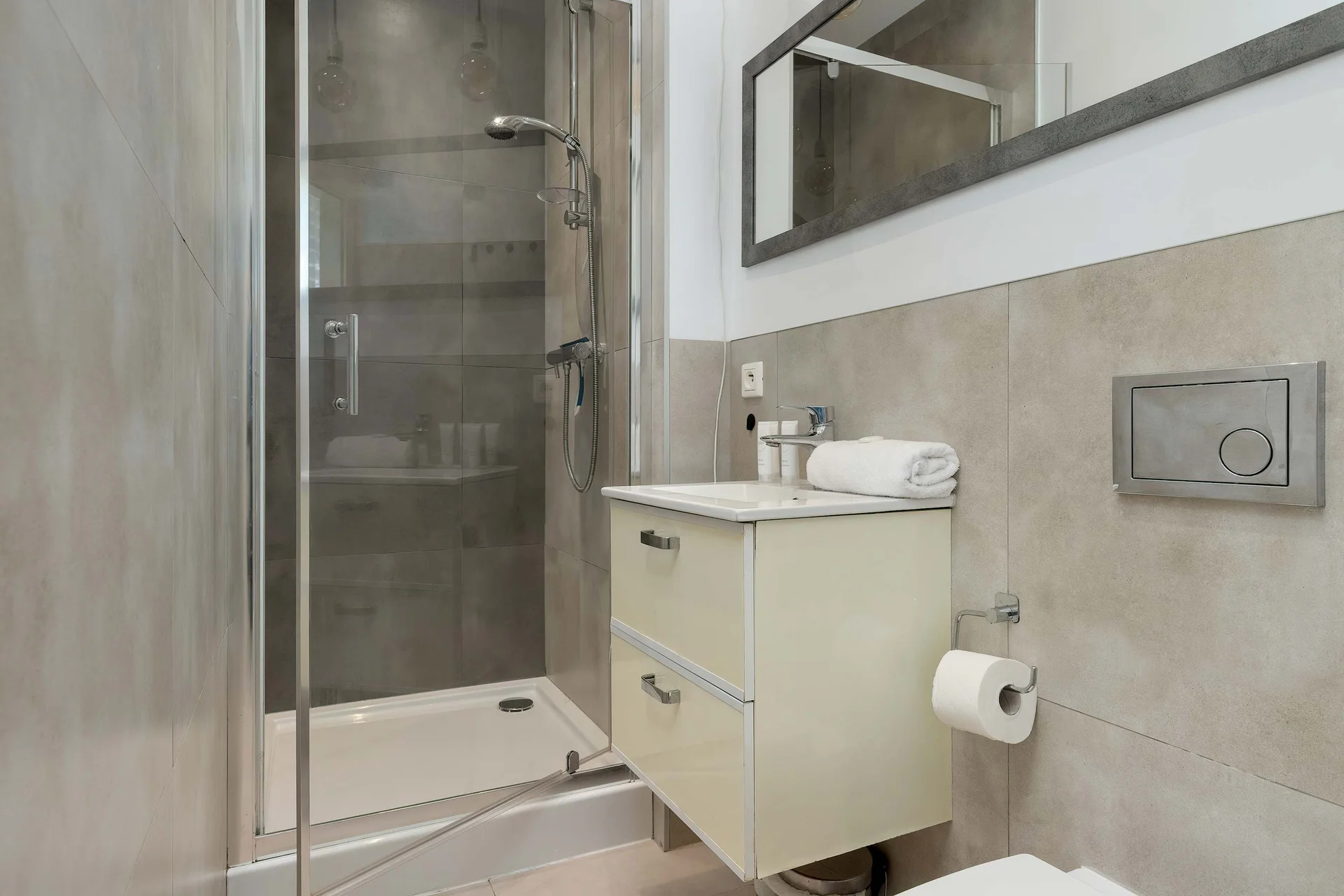 The bathroom's contemporary design includes fresh towels and a hairdryer.