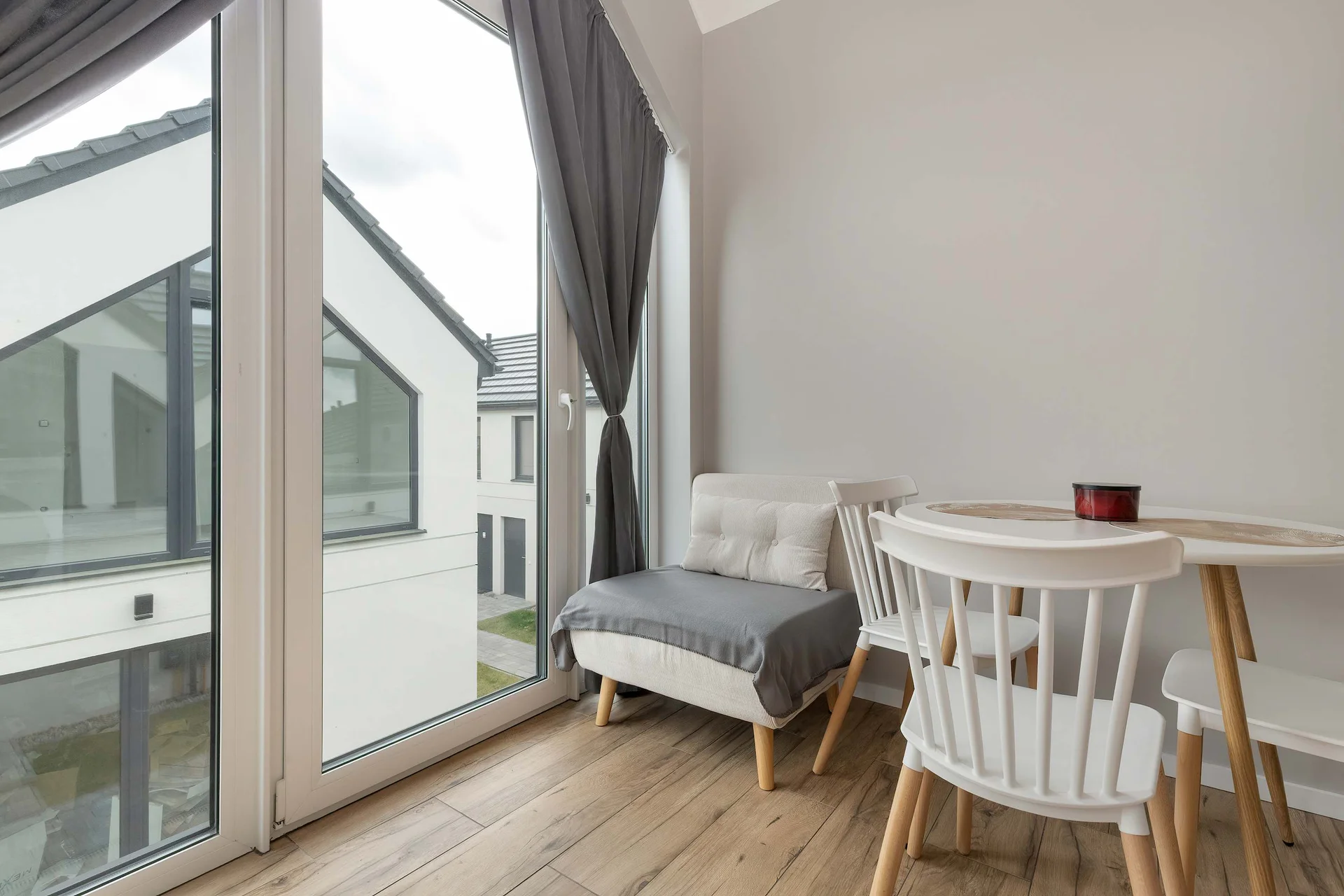 Large gable-end picture windows frame views of neighboring contemporary holiday villas. A wooden dining set arranged beneath the high vaulted ceiling creates an airy, scenic setting for group dinners.