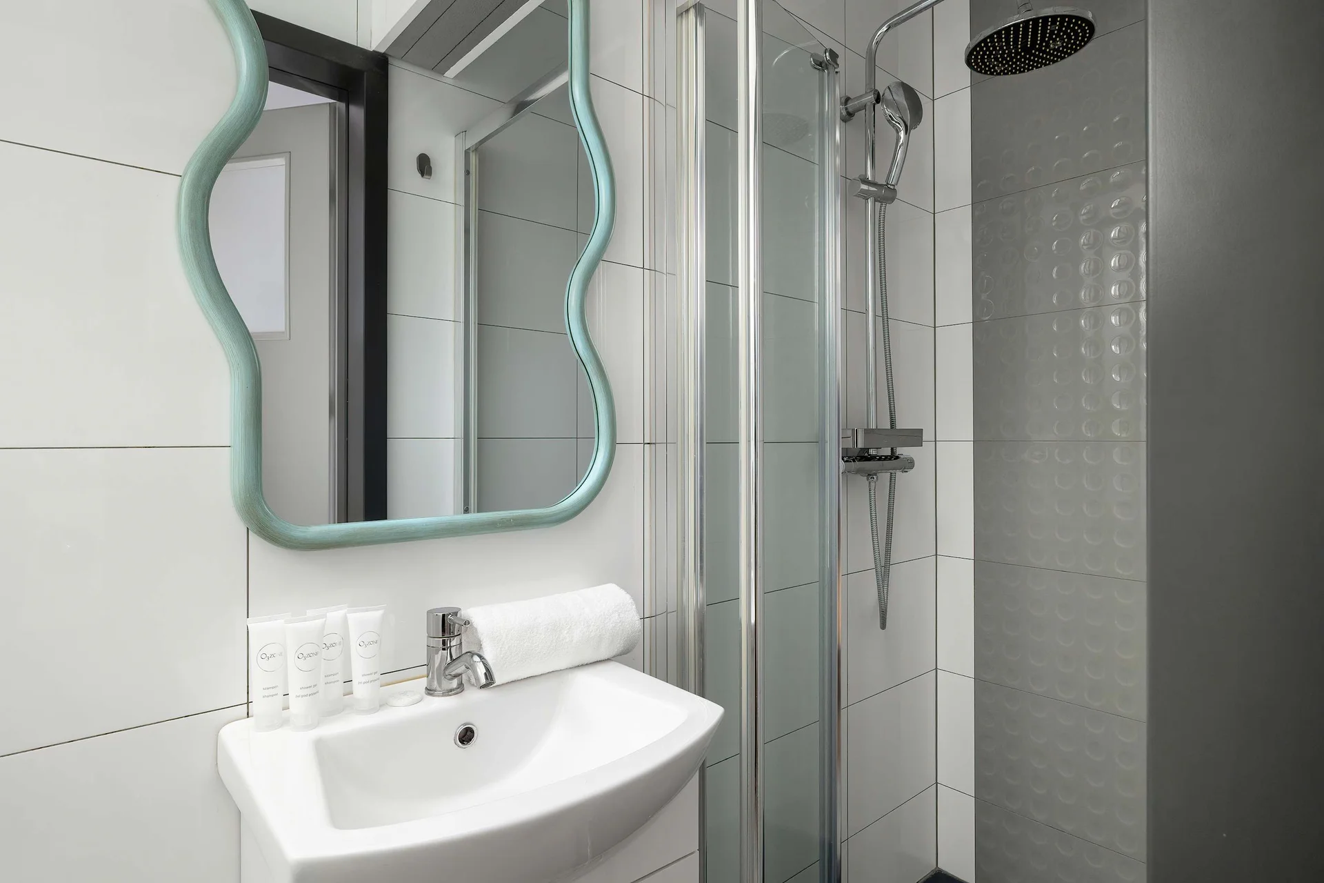 The bathroom's contemporary design includes fresh towels and a hairdryer.