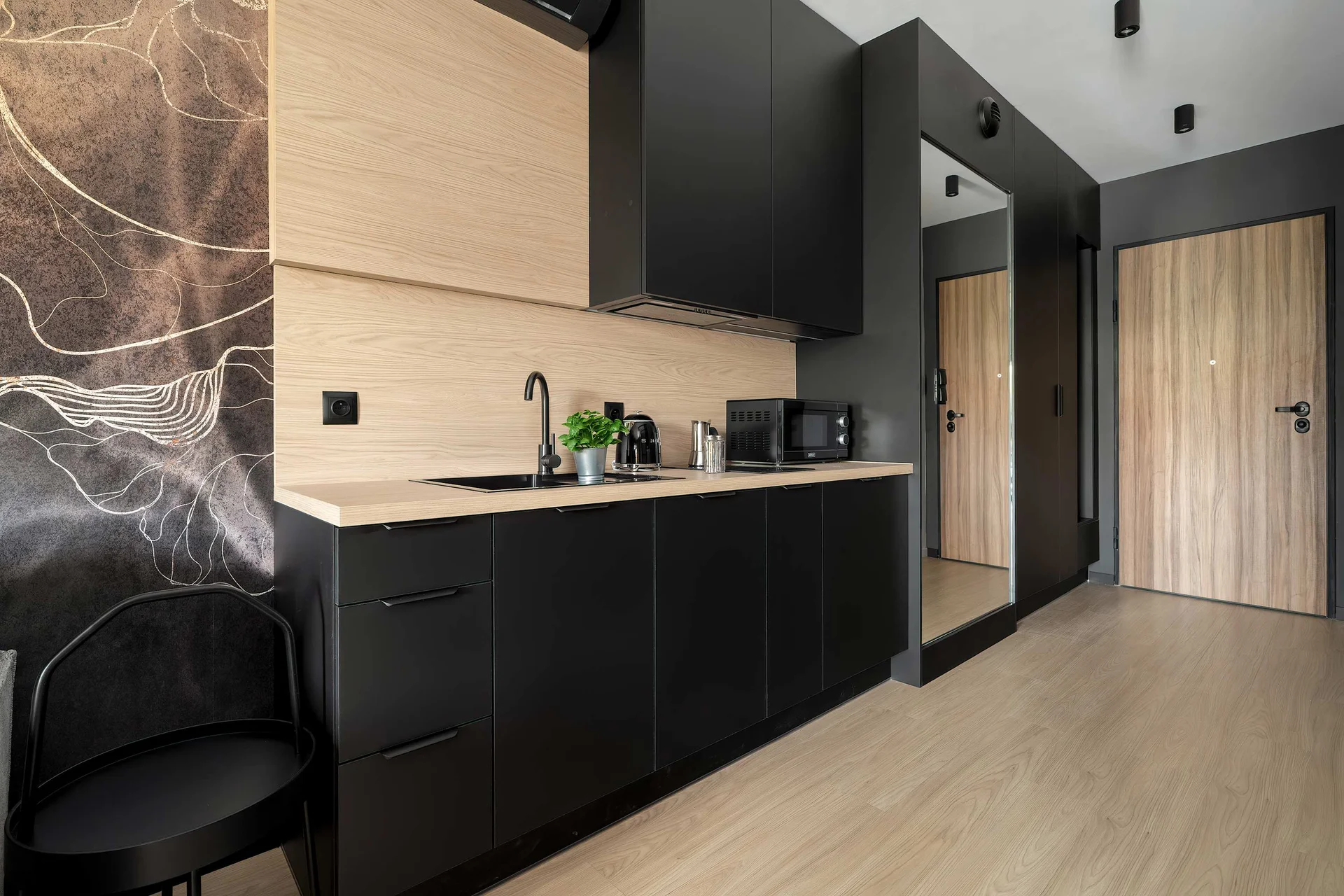 Modern kitchenette with dark cabinets, wood-effect finishes, built-in appliances and plenty of storage space.