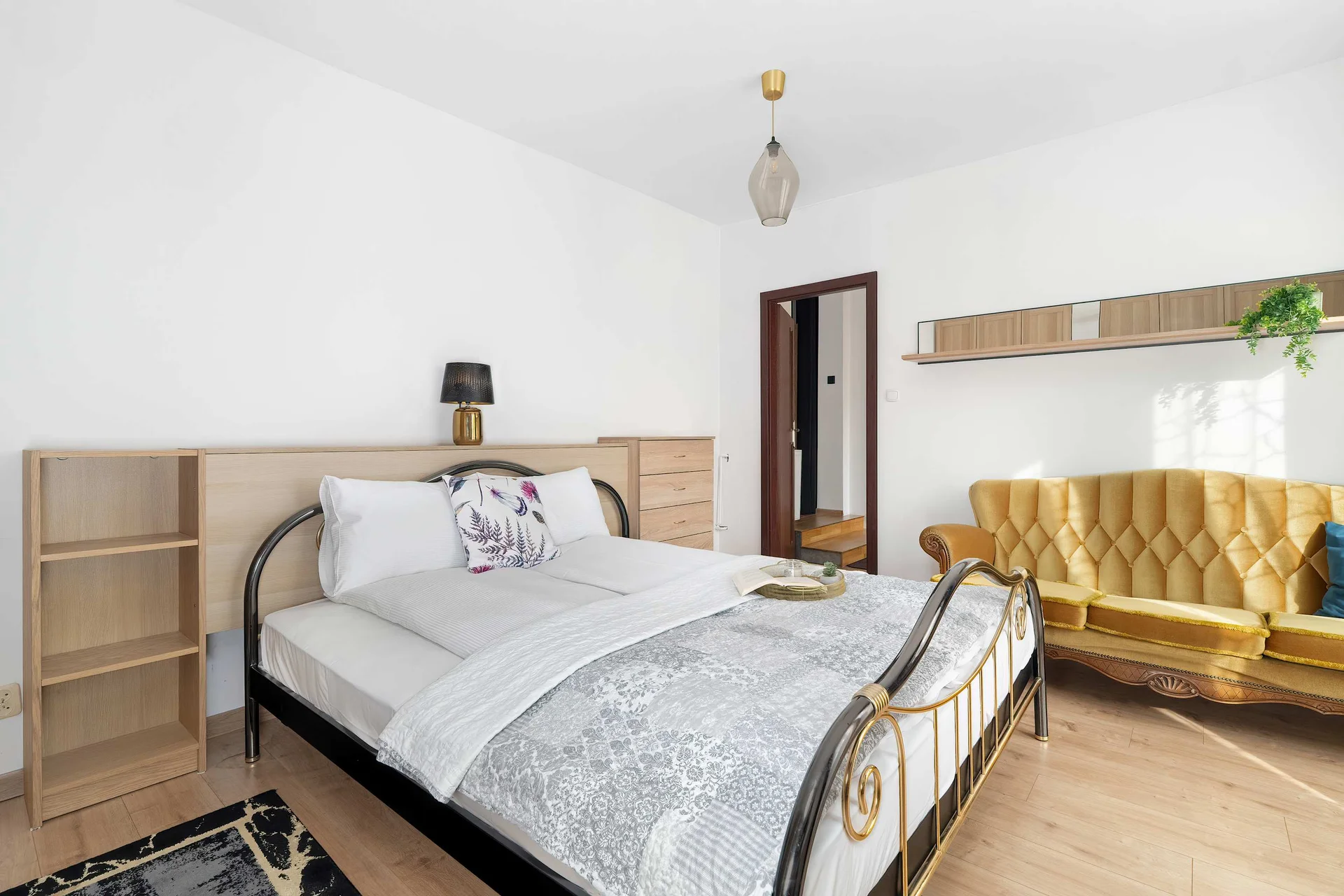 A cozy bedroom with a neatly made double bed, patterned bedding, and a large wardrobe along the wall.