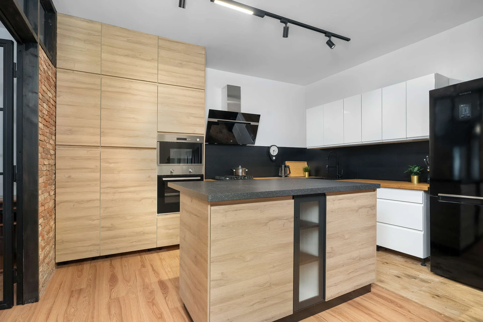 A modern kitchen with wood-effect cabinetry, a black countertop, built-in appliances, and a kitchen island.